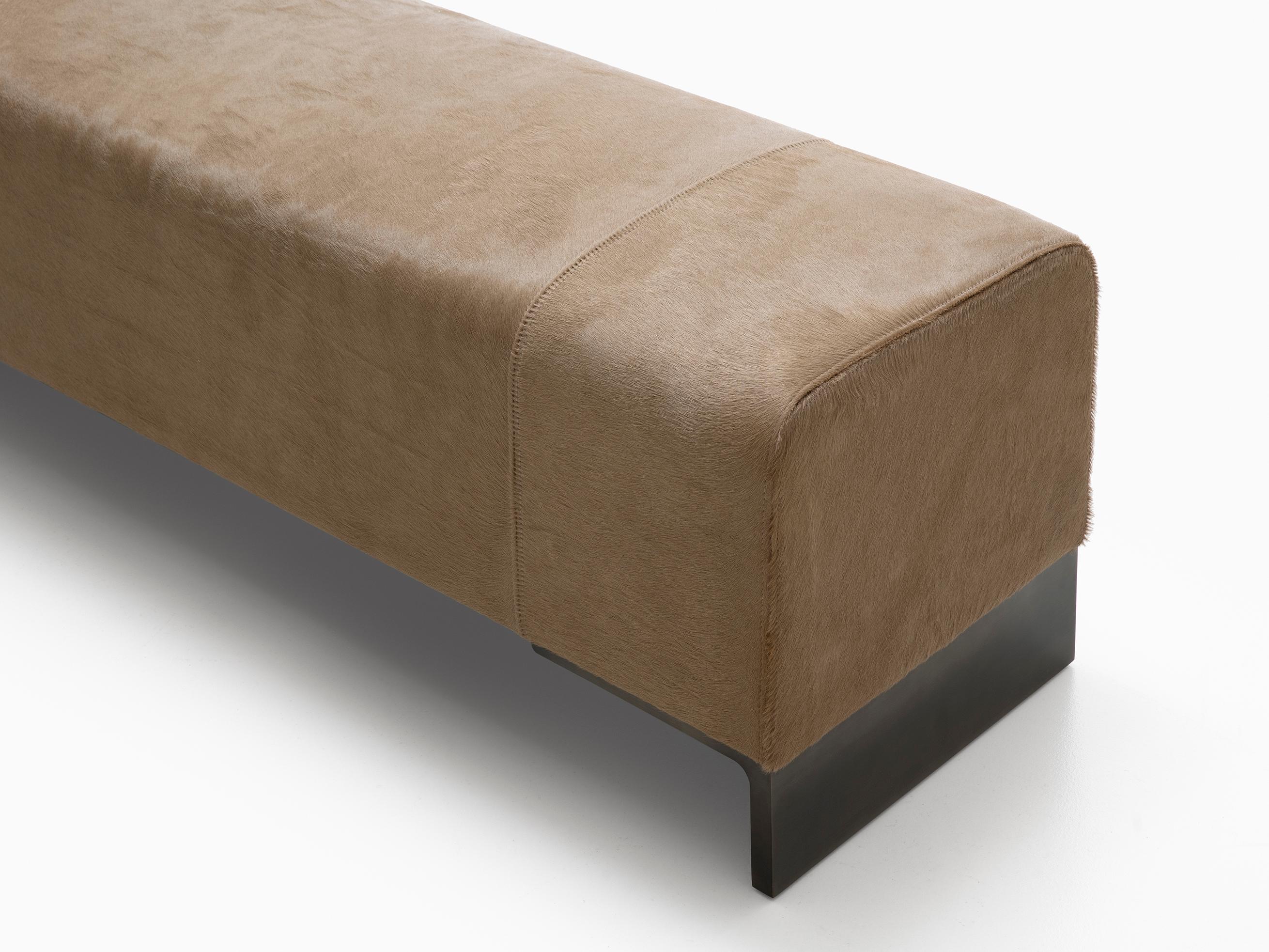 HOLLY HUNT Arakan bench in linden bronze finish with leather upholstery. A voluminous bench that brings gravity and softness to any room, ideal at the foot of the bed. Beautiful and modern with a gorgeous brushed metal base. Upholstered in our