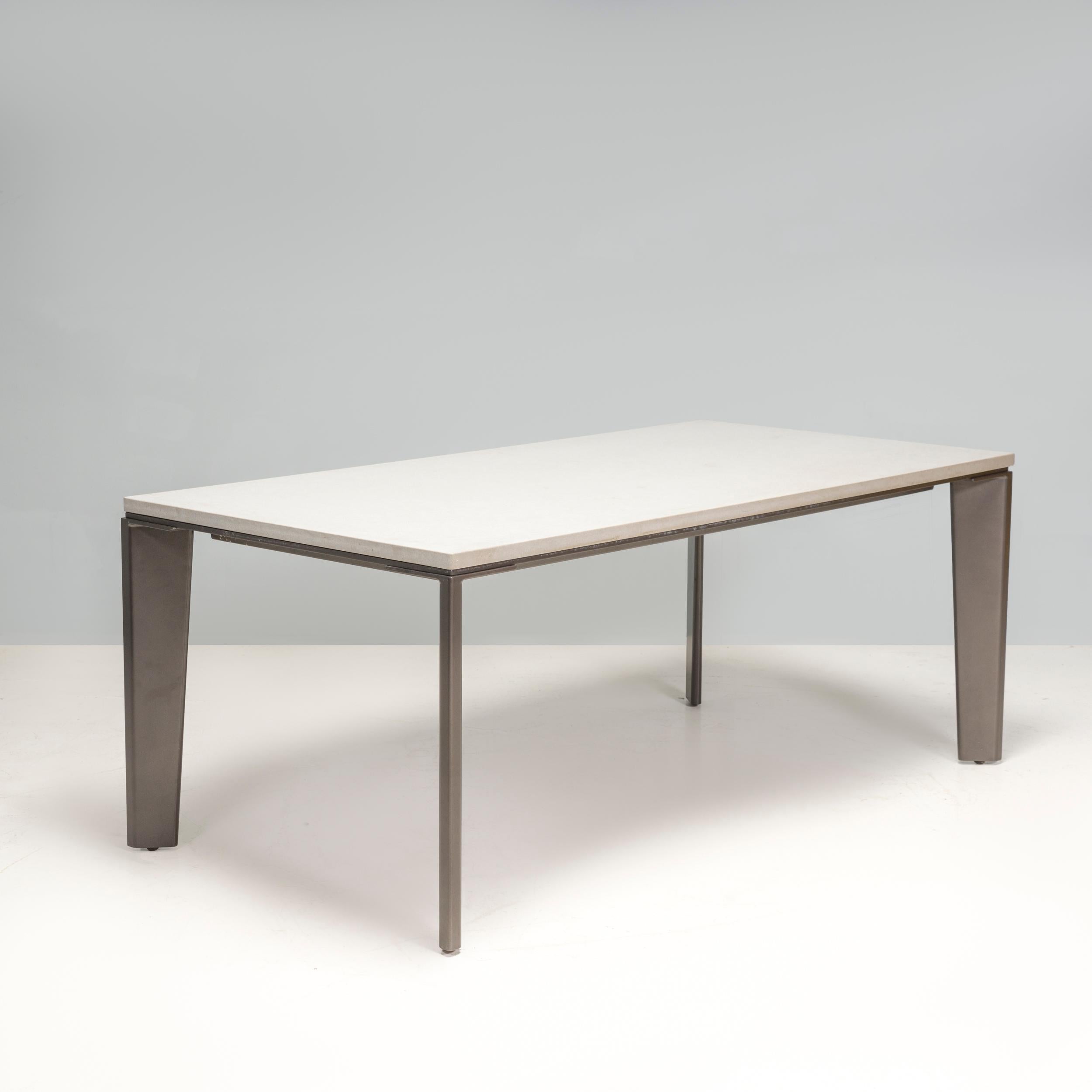 This Keel Outdoor Dining Table was designed by Holly Hunt and made in 2022. Casually sophisticated with a modern aesthetic, it has a rectangular white surface which contrasts with the black supporting structure that border it. 

The angled shape of