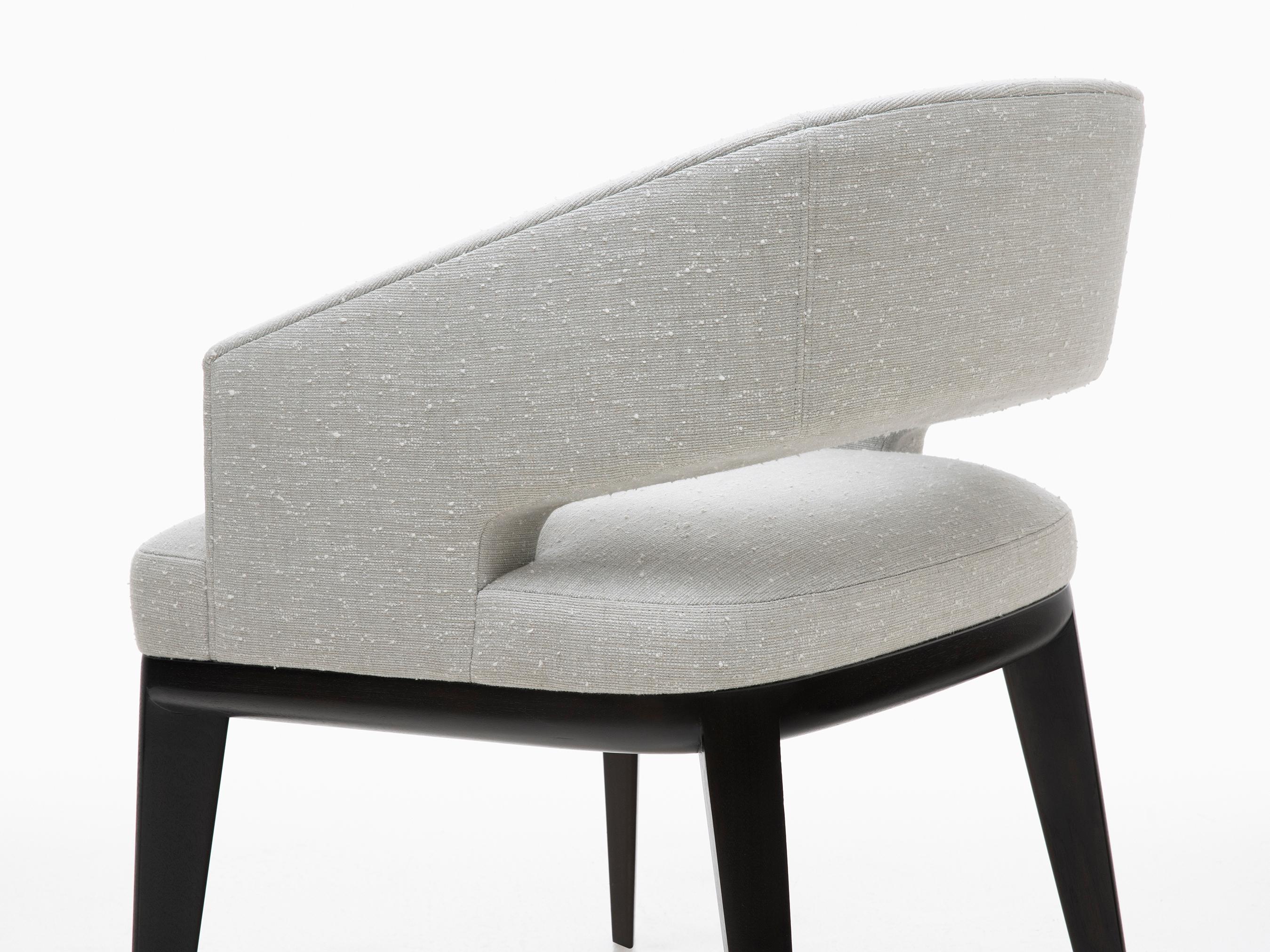 HOLLY HUNT Minerva dining chair in walnut black magic and cloud upholstery. The Minerva’s alluring curves are a harmonious blend of geometric and organic forms. Refined contours of this latest edition in the Minerva series accentuate the details