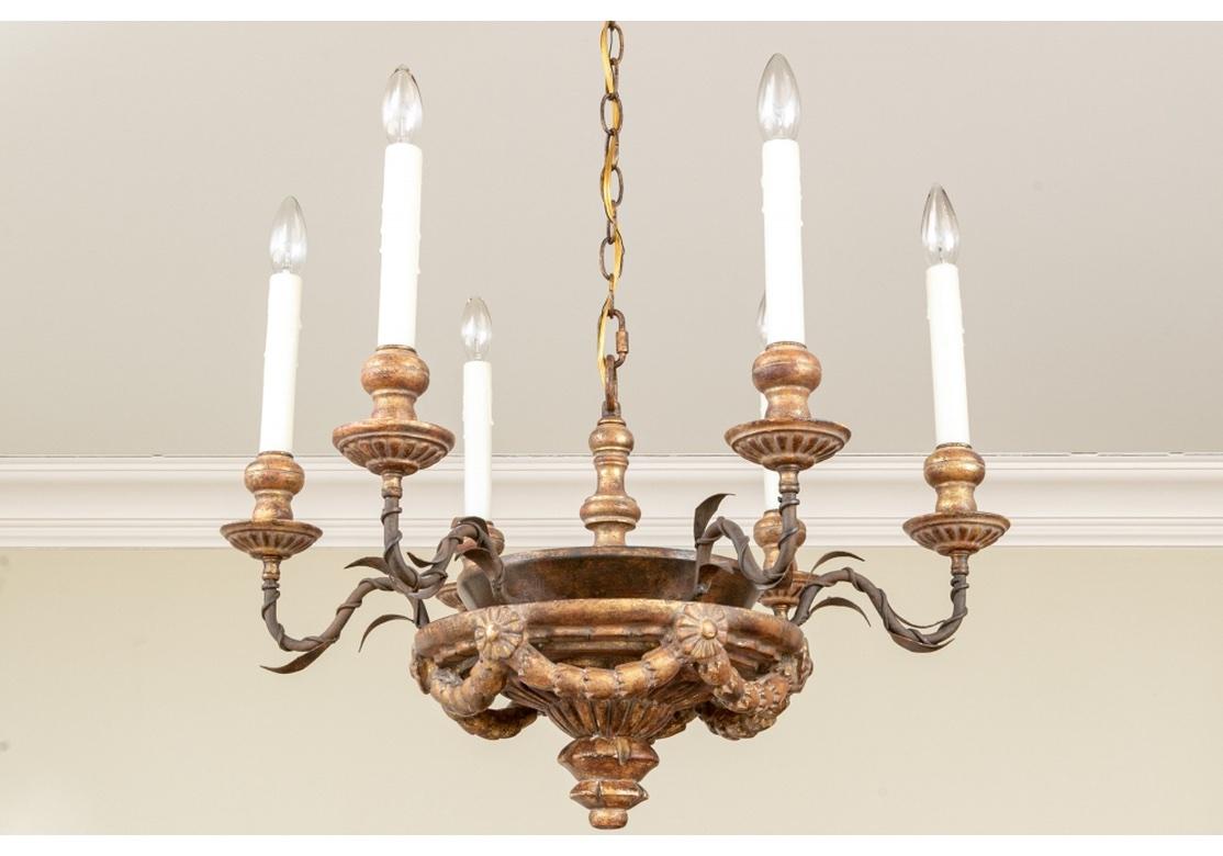 Holly Hunt iron and gilt wood chandelier by Dennis & Leen with round bowl having bell flower and floral drapes with rosettes. The chandelier with 6 iron arms covered with spiral vines and leaves and terminating with fluted bobeche and faux wax