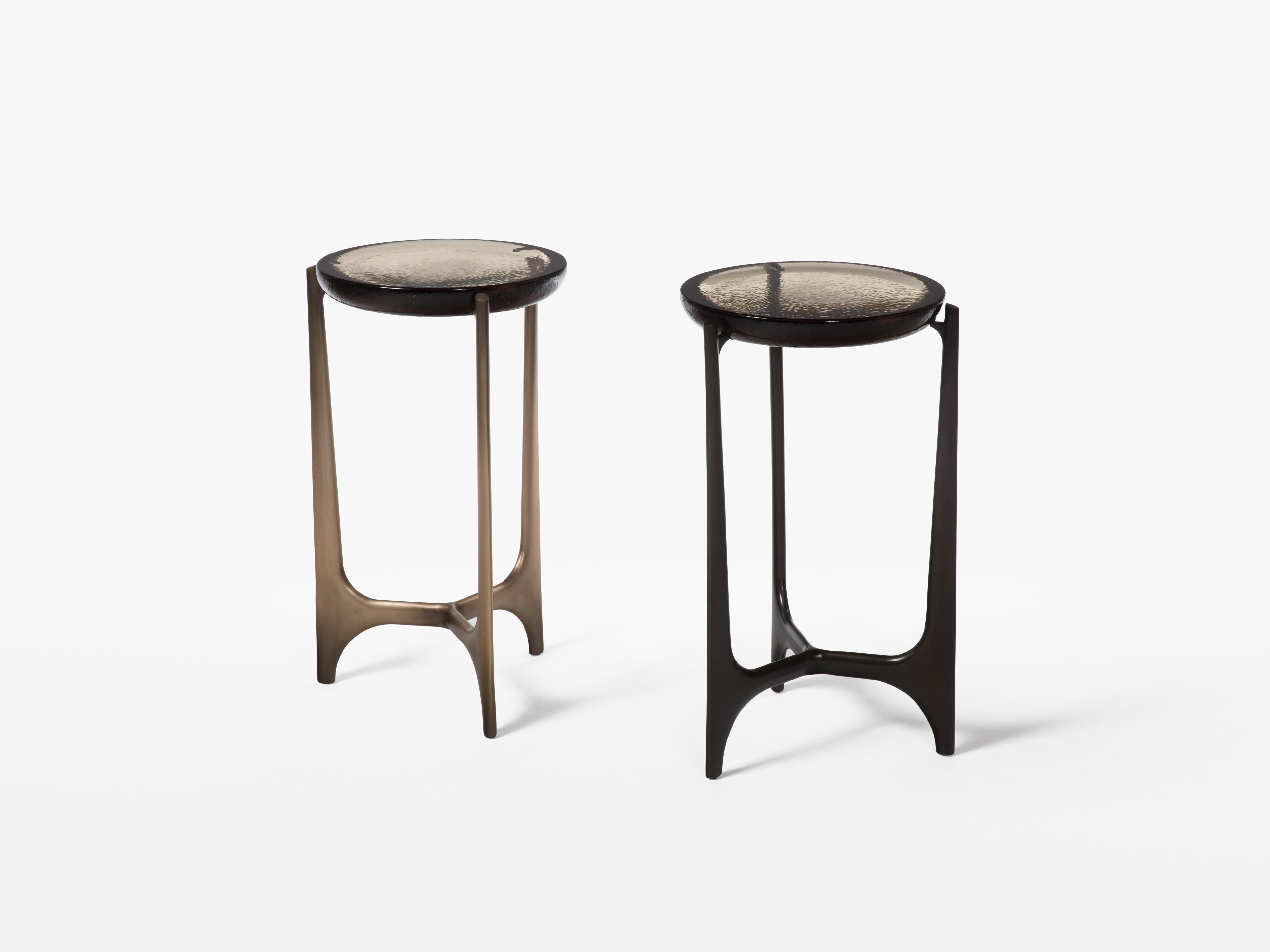 HOLLY HUNT Portia drink table with fog cast glass top and dark bronze base. Inspired by the free-flowing modernism of Oscar Niemayer, the Portia is at once elemental and otherworldly. Its bronze base, available in both light and dark monument
