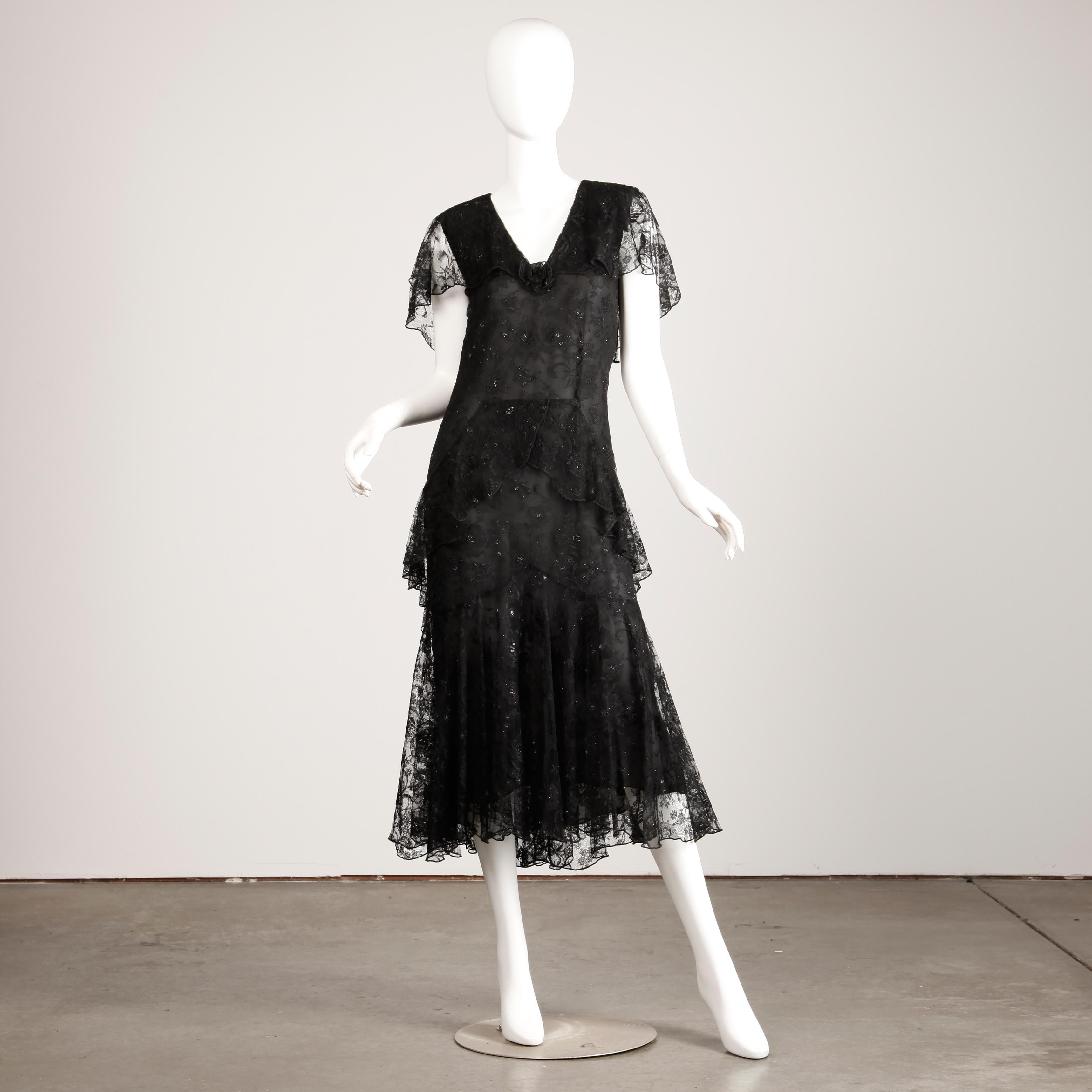 Vintage designer dress by Holly's Harp from the 1980s-90s done in black lace with metallic thread. 1920s Flapper-inspired cut with flutter sleeves and drop waist. Fully lined with single button closure at the back of the neck. There is no marked