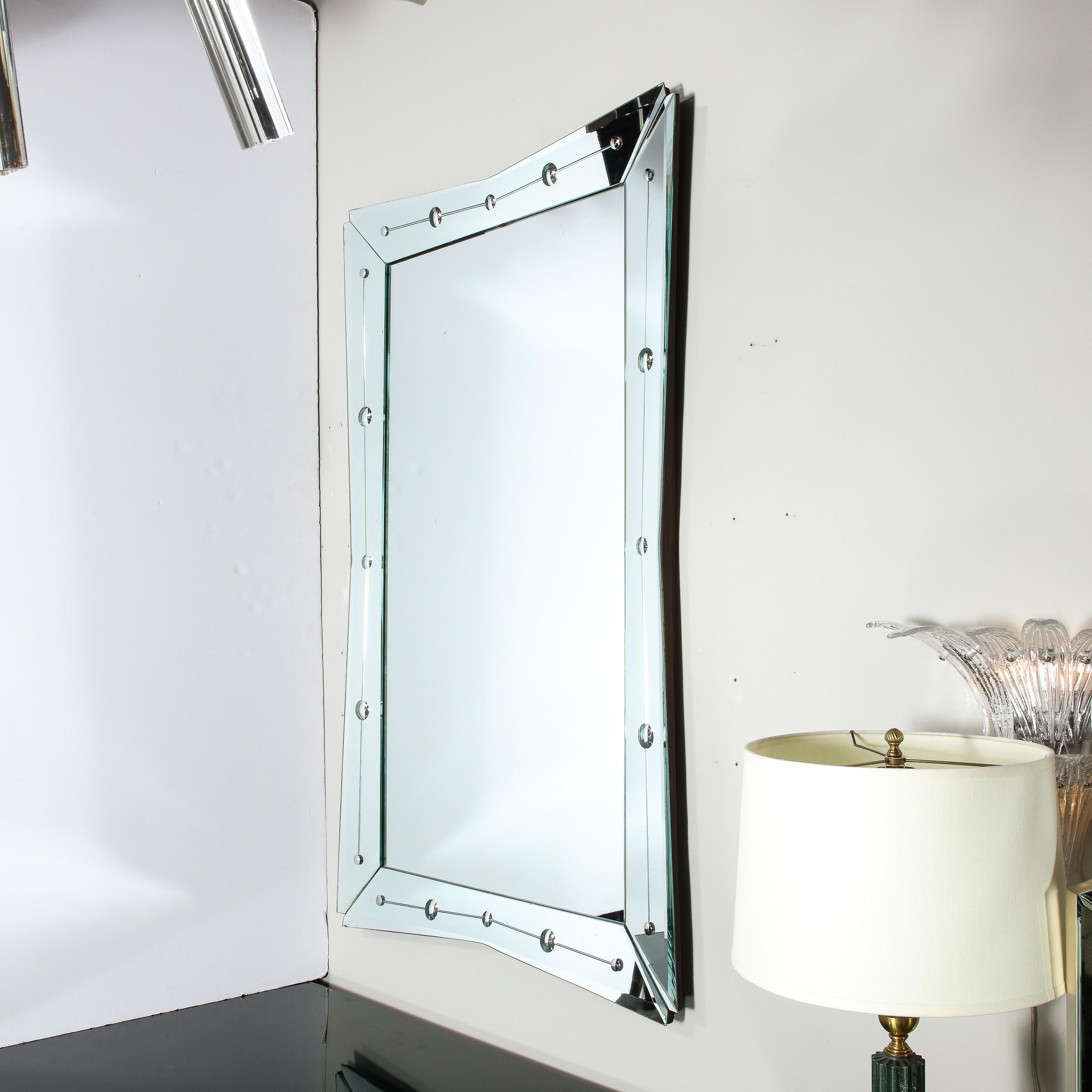 This stunning Art Deco Hollywood mirror was realized in the United States circa 1945. It features an atomic silhouette with four rhombus form mirrored segments adjoined around a rectangular mirrored panel. The perimeter segments taper in the center