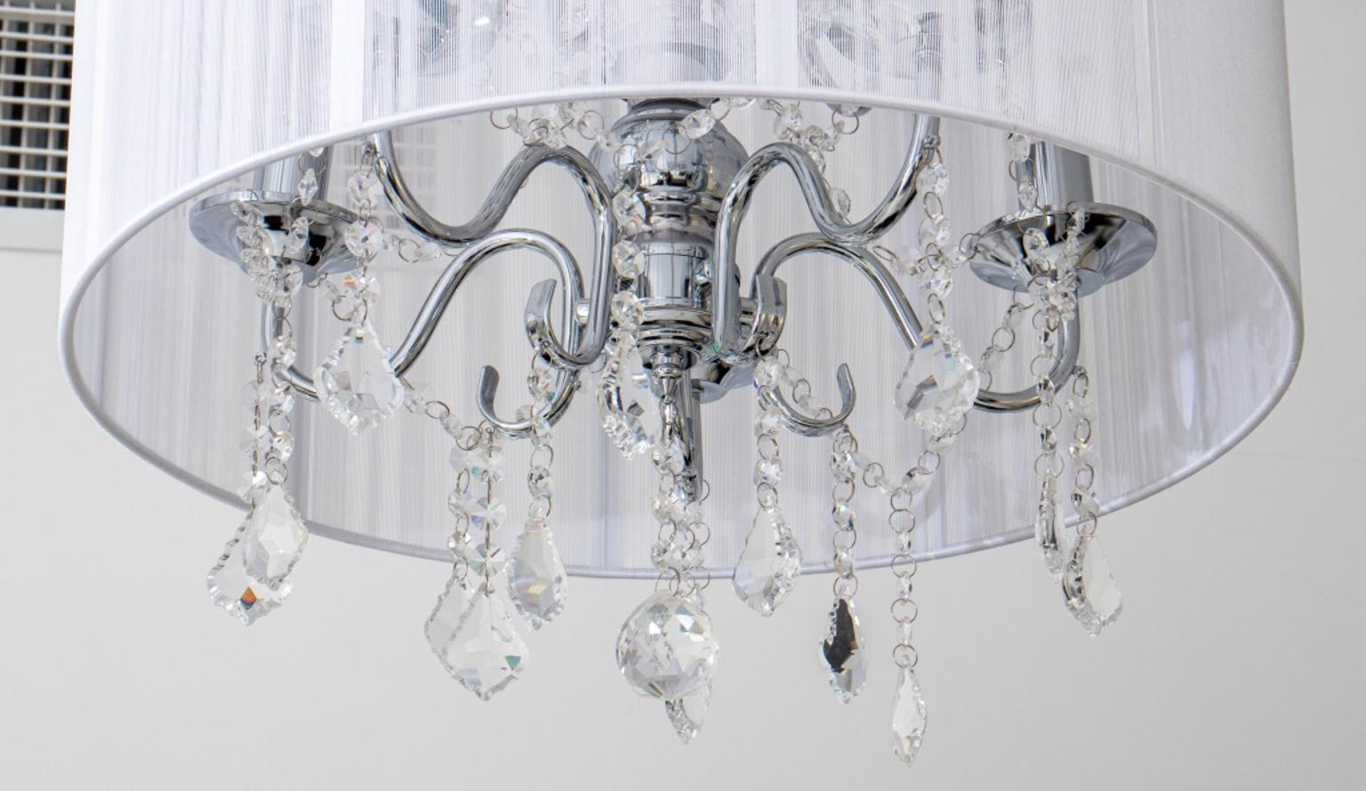 Modern Hollywood Glam chandelier with colorless crystal drop pendants, white string shade, and ten silver-tone metal arms terminating in candlestick form lights. 45