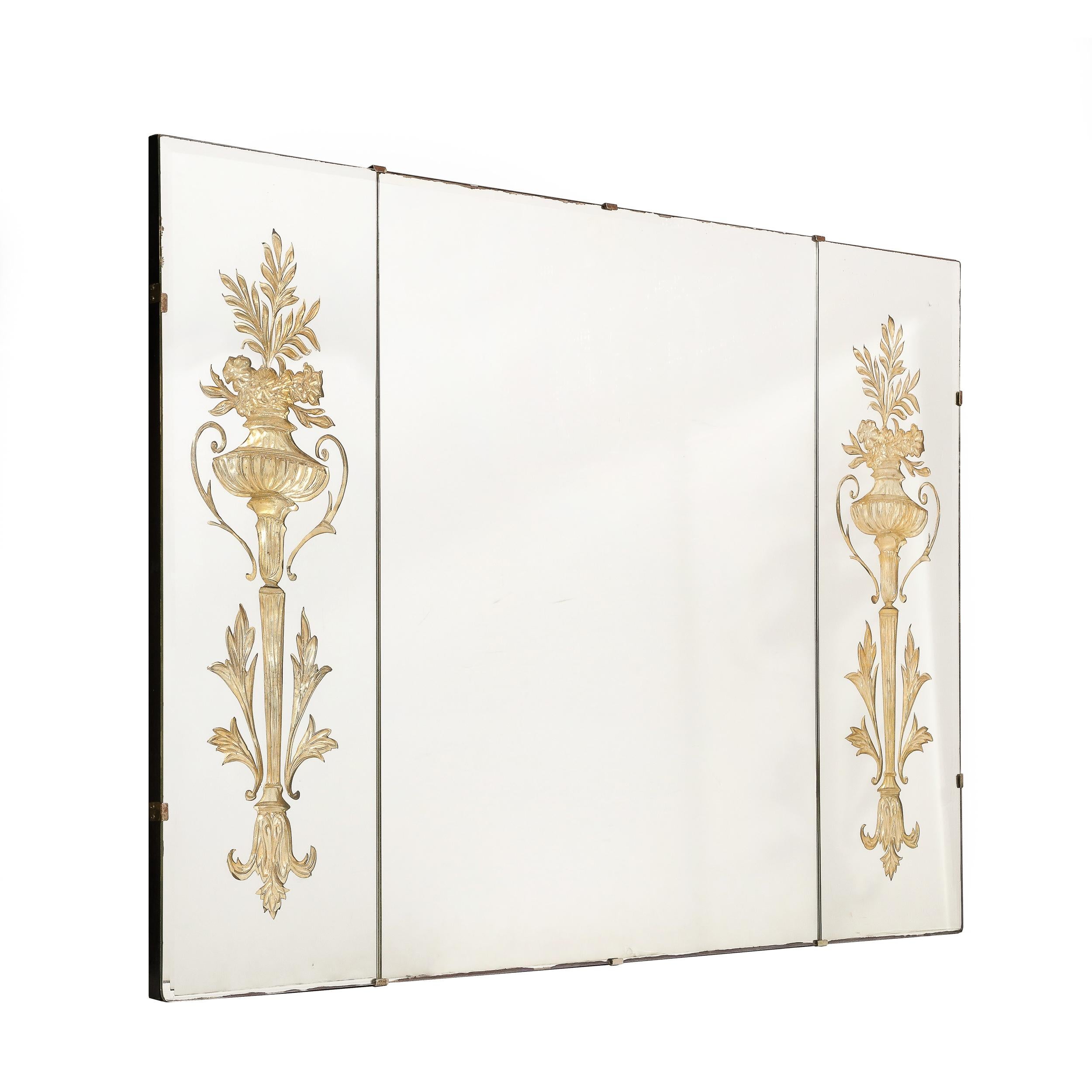 This alluring Hollywood Regency Three-Paneled Mirror with Gilt Eglomise detailing originates from the United States, Circa 1940. Featuring three panels joined to the backing with subtle curved brass fittings, the side panels feature Neoclassical