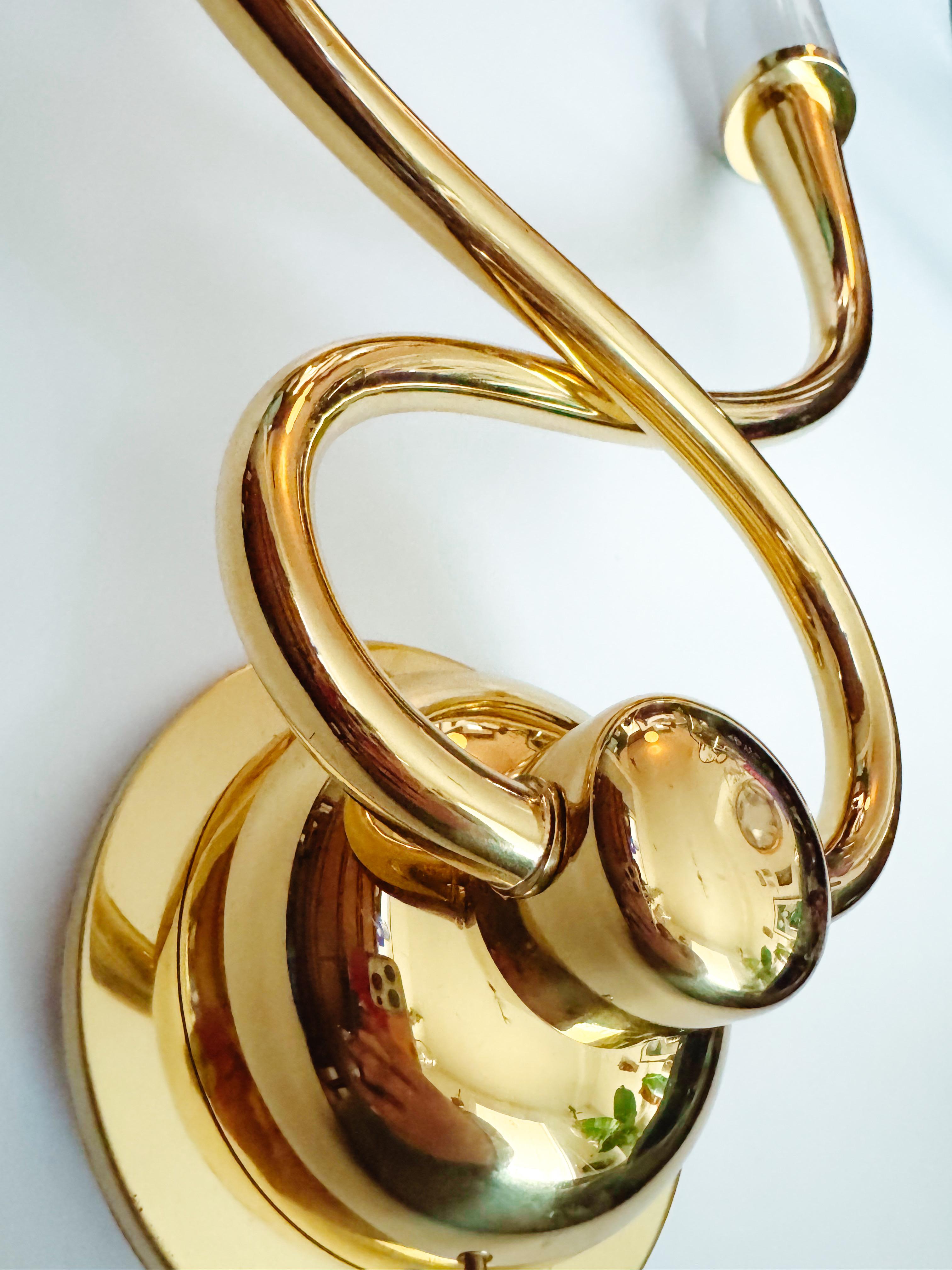 Elegant and refined, this set of four Egoluce wall sconces from Italy, circa 1980s, showcases a beautiful blend of brass structure and frosted glass shades, offering a timeless design that complements both modern and traditional interiors. Unlike
