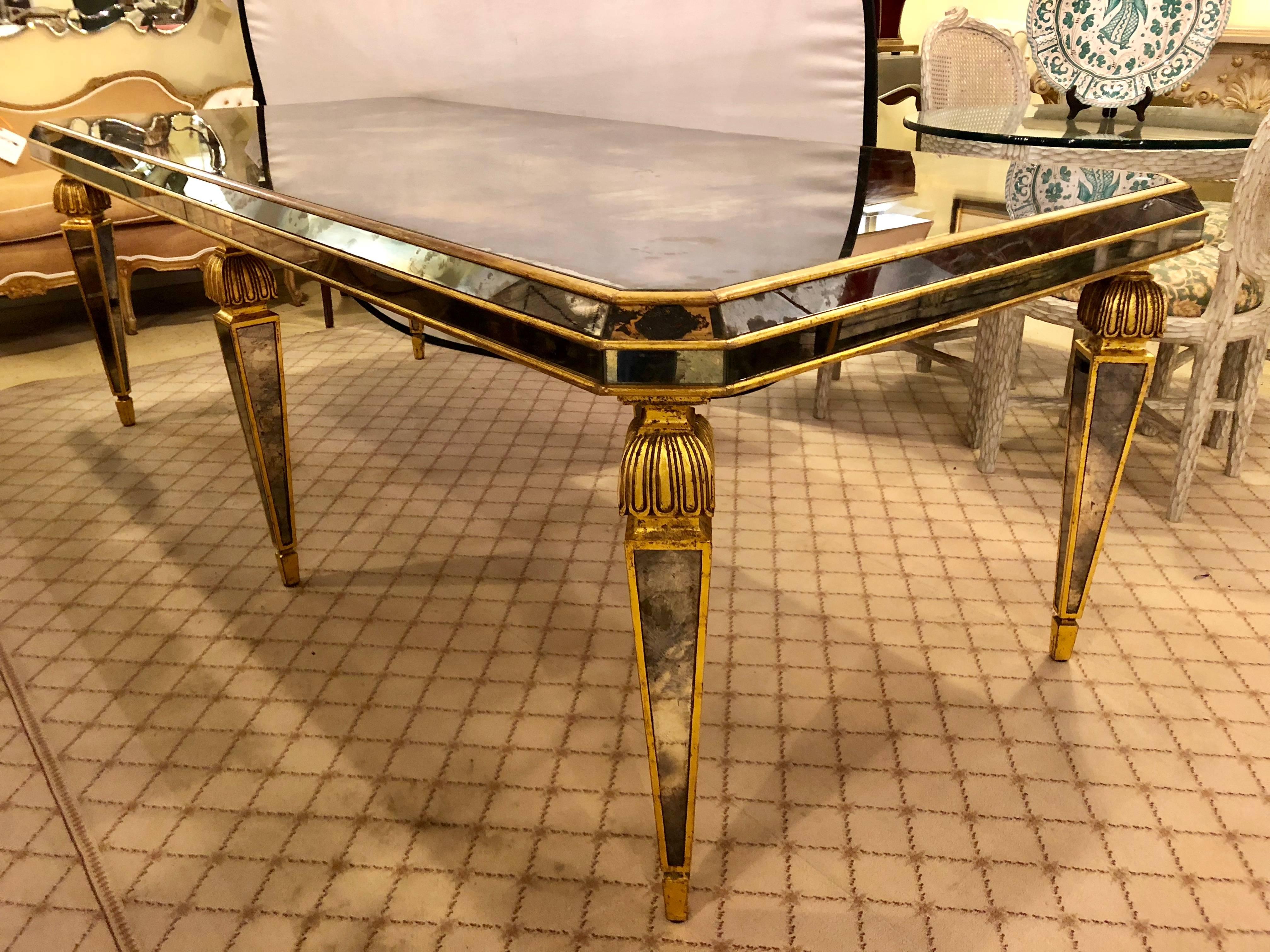 A fine custom quality spectacular Hollywood Regency antiqued mirrored dining / conference table. This finely gilt custom quality wooden dining table has an all over antiqued mirror insert. The giltwood sabots leading to a group of tapering mirrored