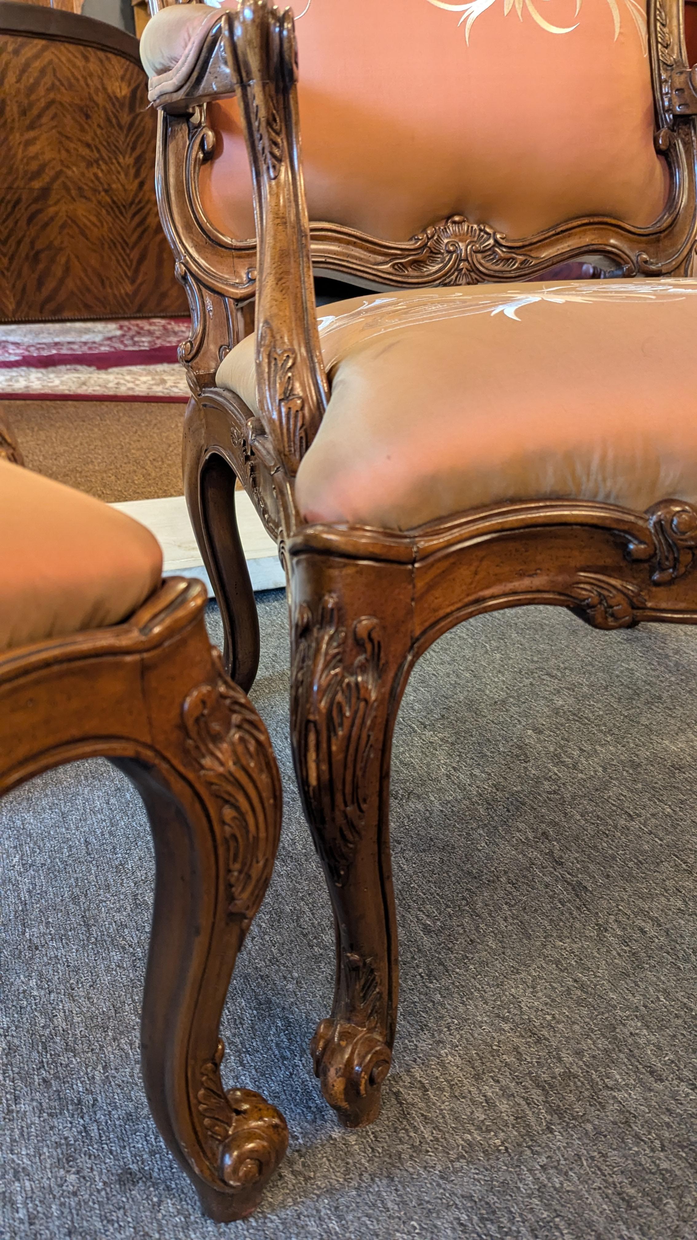 Paire de chaises de style Louis XV Hollywood Regency magnifiquement sculptées. La tapisserie d'ameublement est une magnifique broderie crème filigrane sur un tissu pêche-or chatoyant qui semble être de la soie, mais qui pourrait être de la rayonne.