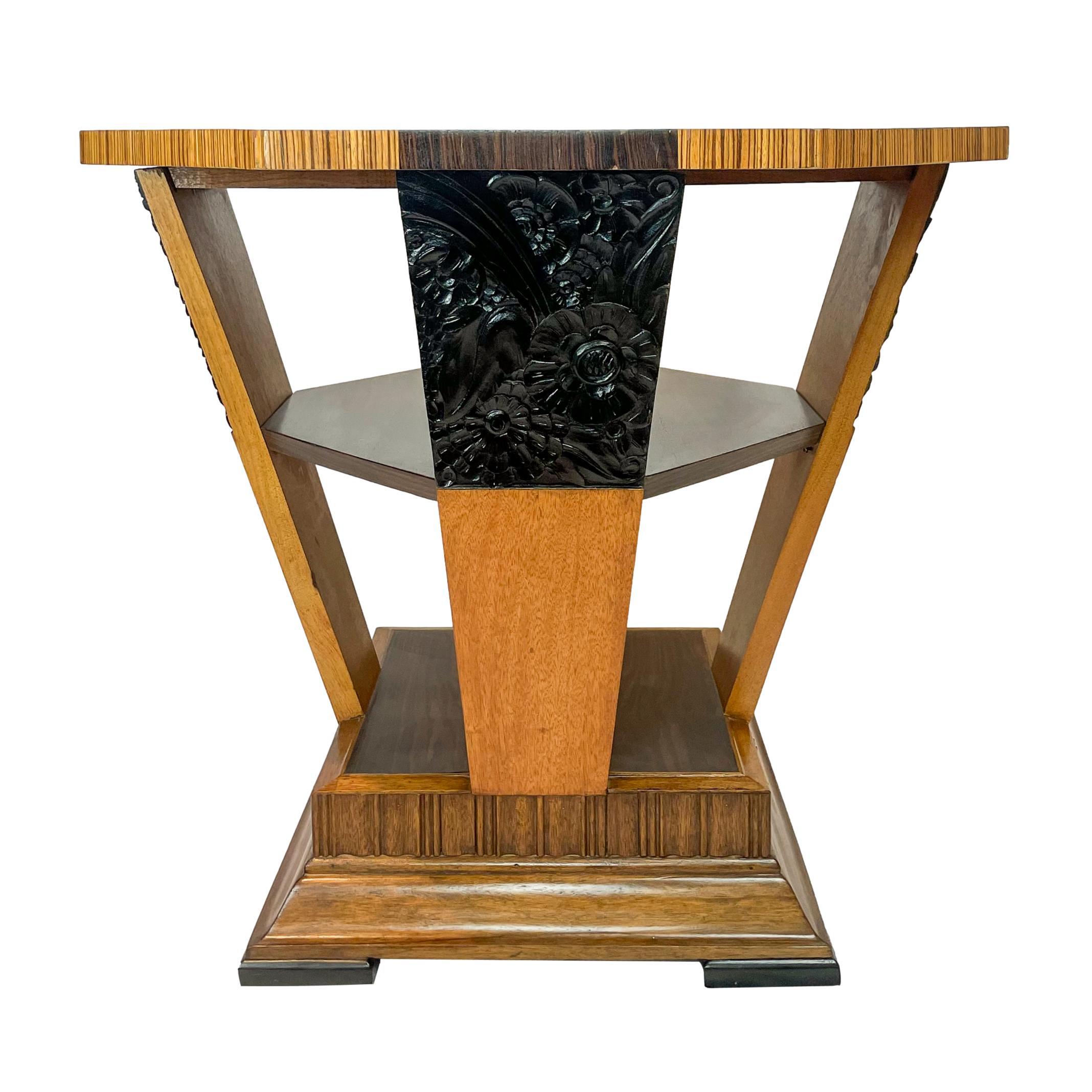 Art Deco center table of Octagonal Form, the top inlaid with alternating Macassar ebony and rosewood sections, supported by four tapering and inward slanting maple panels, the capitals with stylized flowers carved in ebony, with a central inset