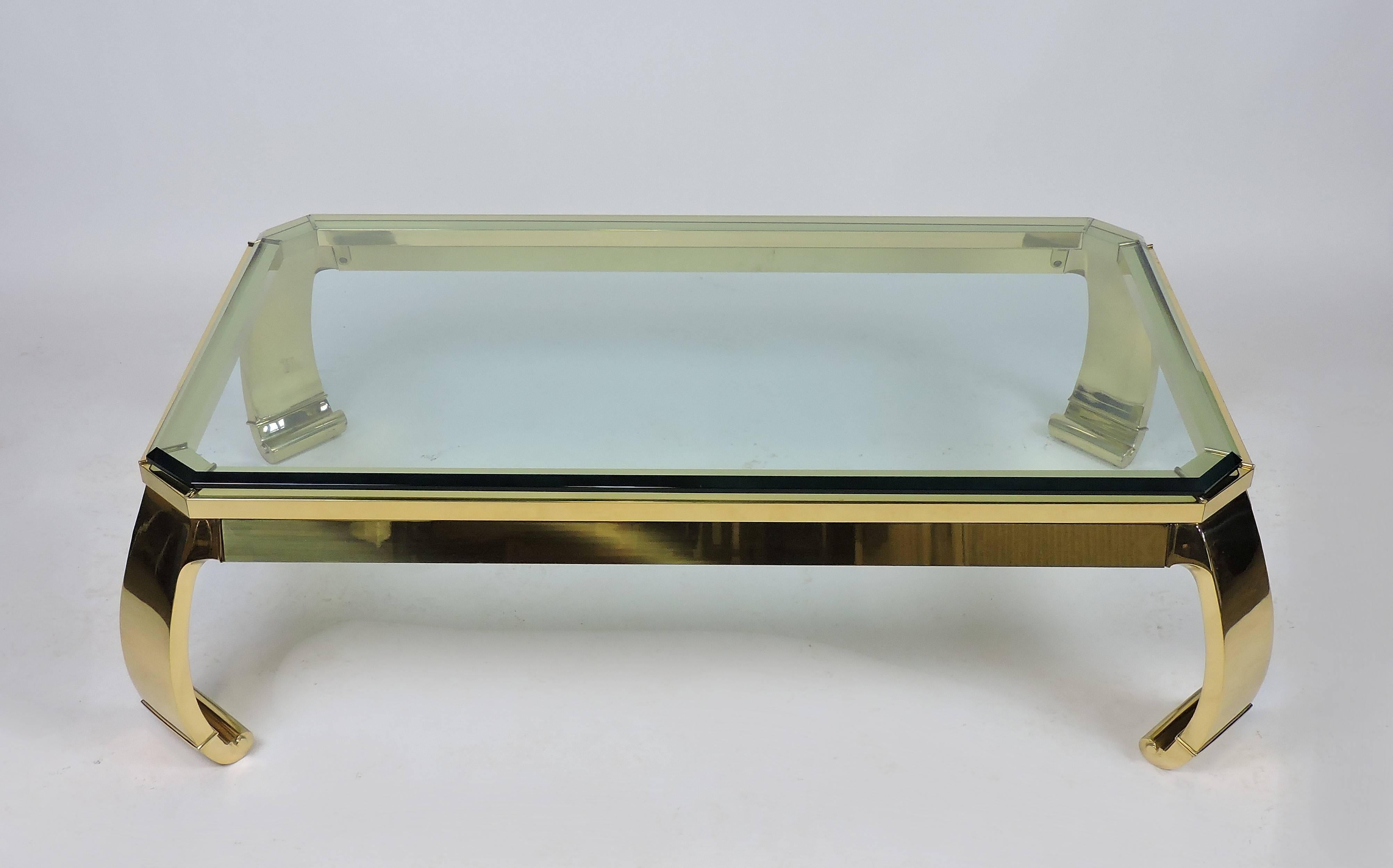 Beautiful and top quality Asian Style Italian brass and glass coffee table. This heavy and well made table has a solid brass base with a three-quarter inch thick beveled glass top. It has a nice clean design with scrolled legs that give it a modern