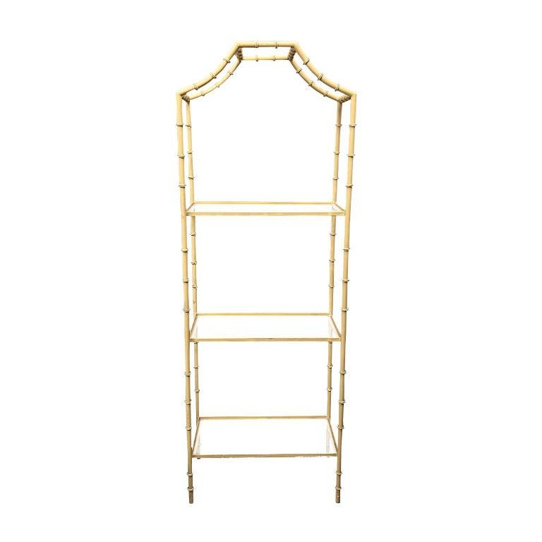 A Hollywood regency faux bamboo etagere or bookshelf. Created from metal and painted in pale ballet pink, this shelf will be a great addition to any grandmillennial's home. There are three glass shelves that are newly cut and in excellent condition.