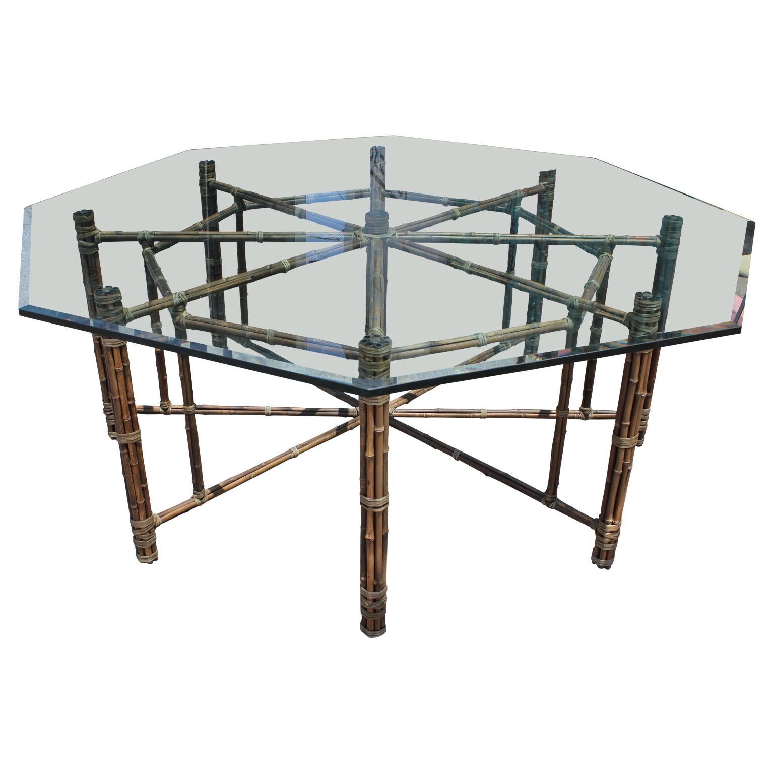 Gorgeous Hollywood Regency style dining table made from bamboo / rattan with an octagonal bevelled glass top by Mcguire and in the style of Mastercraft.
