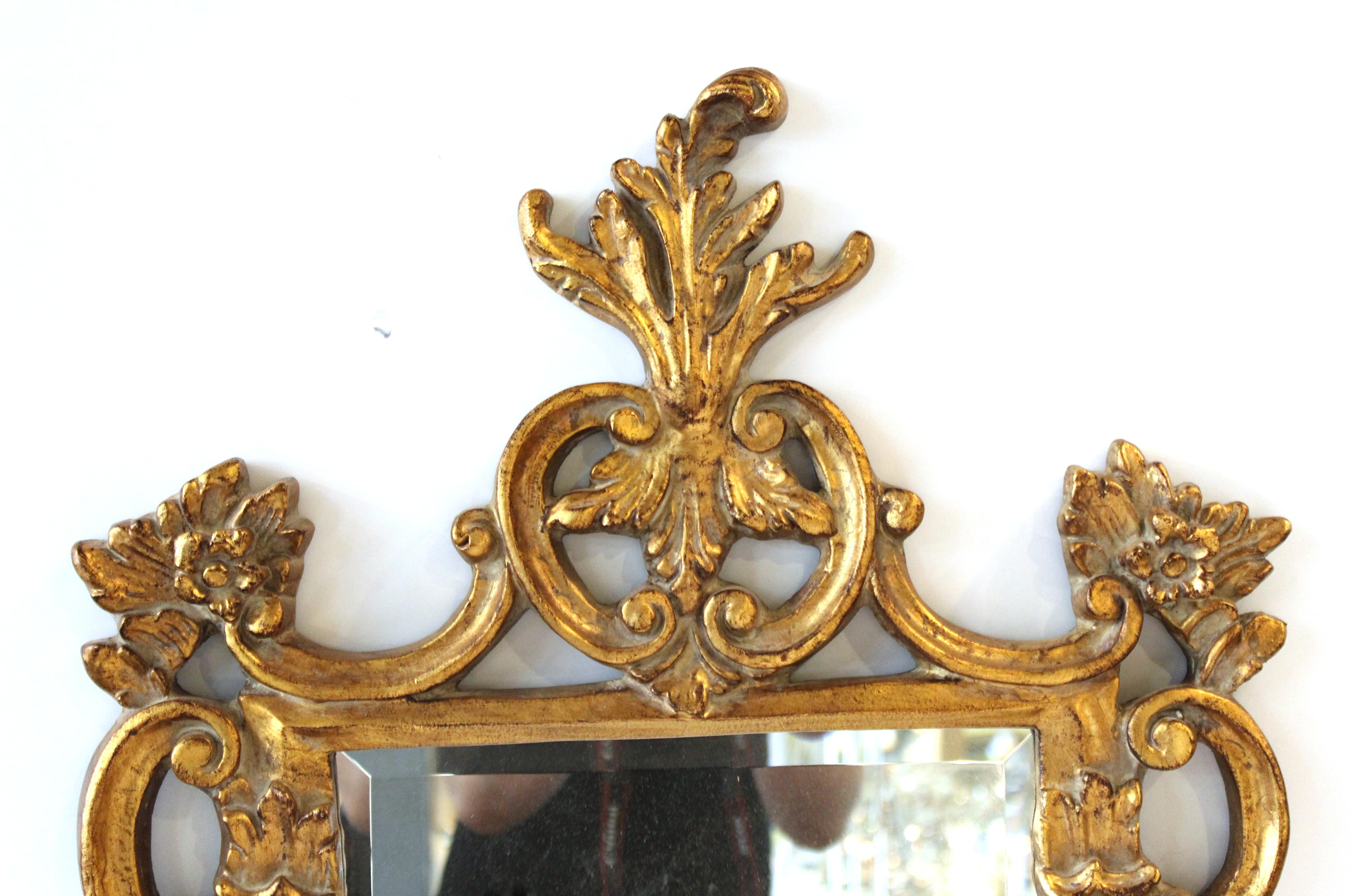 Hollywood Regency Baroque style wall mirror with ornamental giltwood frame with swags and foliage. The piece is in great vintage condition with age-appropriate wear.