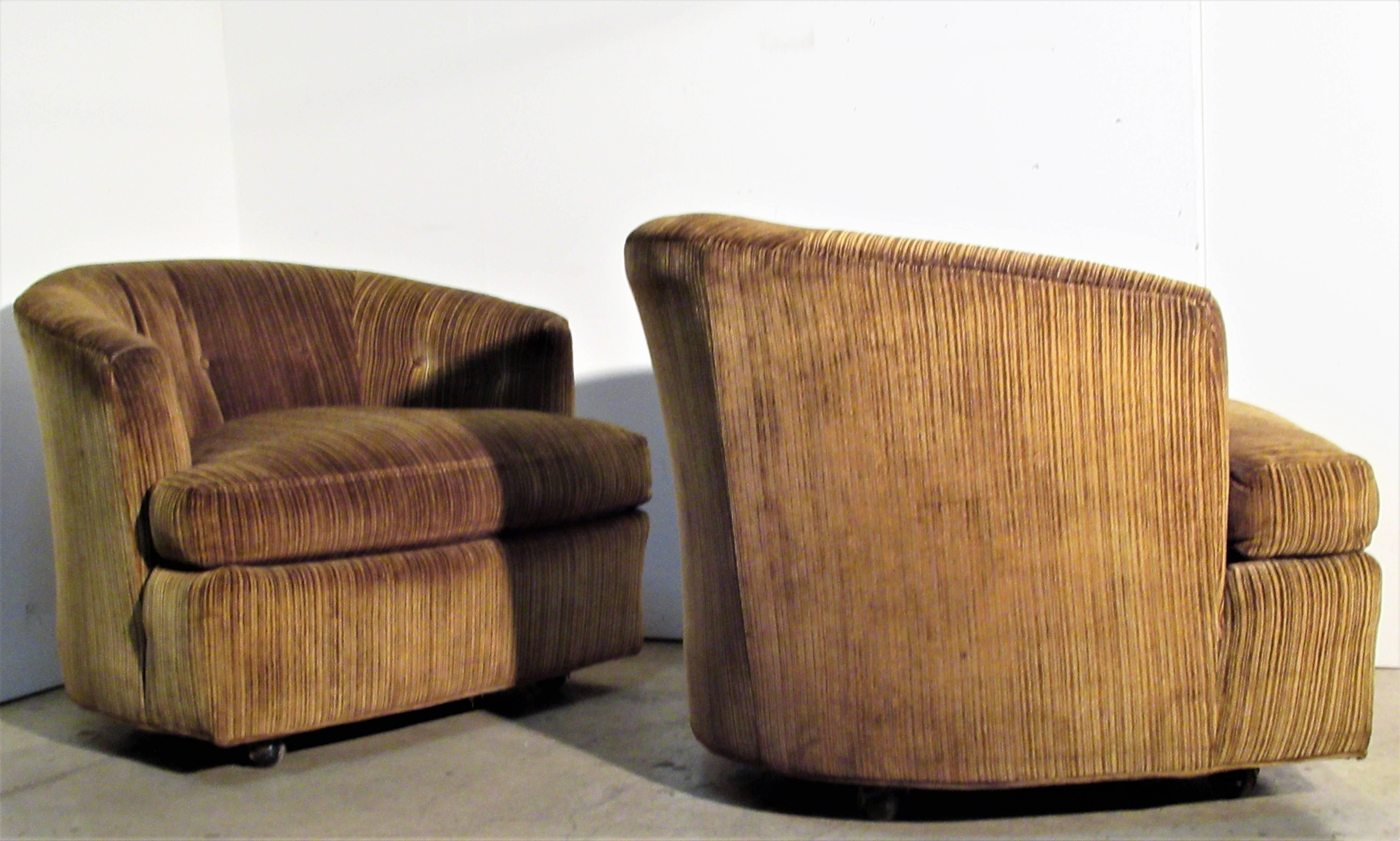 A pair of Hollywood Regency rolling button tufted barrel form lounge chairs in original two-tone ribbed textured cotton felt upholstery. Beautifully proportioned chairs that look great from every angle. Structurally solid and comfortable, circa