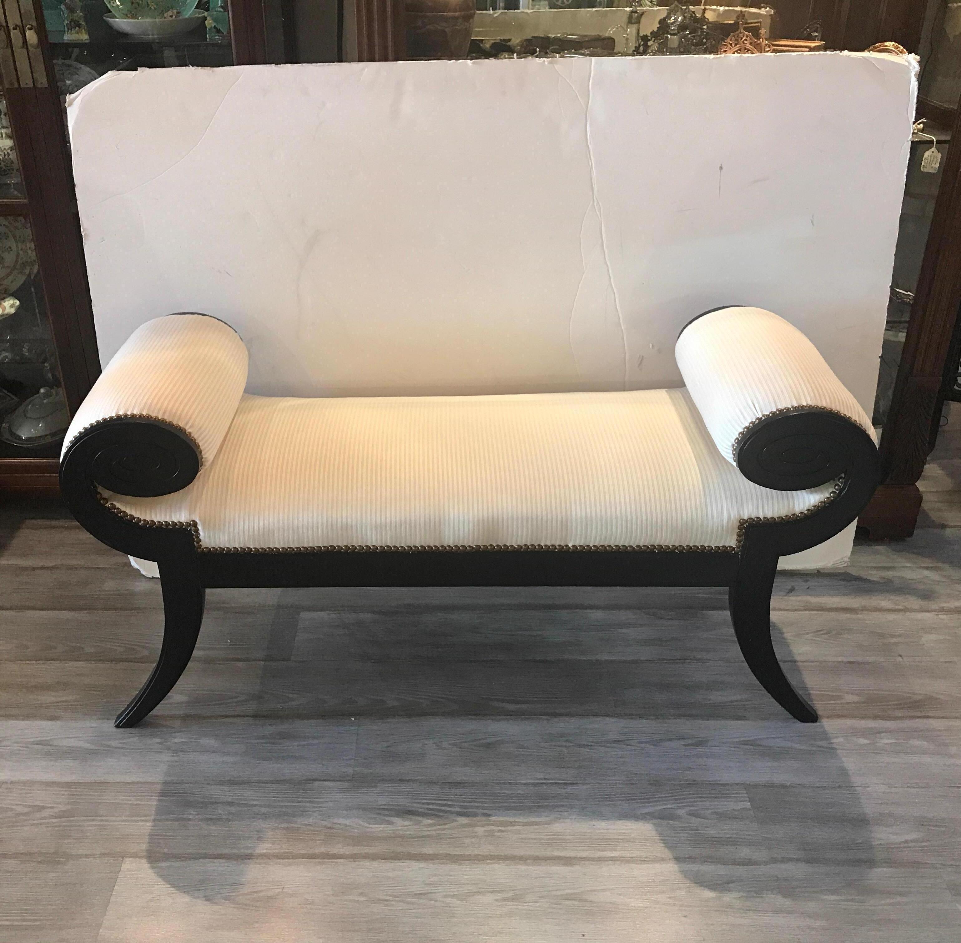 Glamorous black and white Hollywood Regency rolled arm bench. In the manner of James Mont, the ebonized frame with oval bolster style arms with carved detail newly covered in an oyster tone on tone stripe fabric.