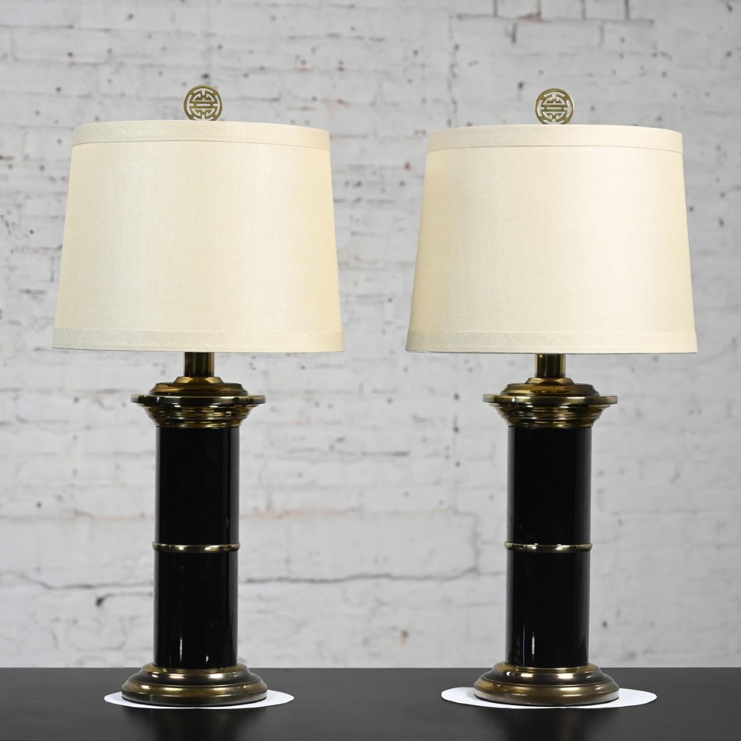 Incredible vintage Hollywood Regency black enameled metal & brass plated detail column table lamps with brass Asian finials and new tan hardback fabric tapered drum shades, a pair. Beautiful condition, keeping in mind that these are vintage and not
