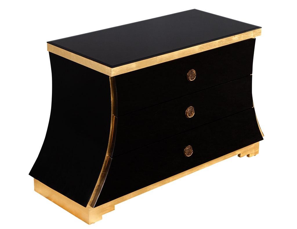 Hollywood Regency black glass and gold leaf curved commode. America circa 1980’s, unique curved design. Composed of wood and black glass with beautiful gold leaf detailing on trim. In great condition with extremely minor wear difficult to see on the
