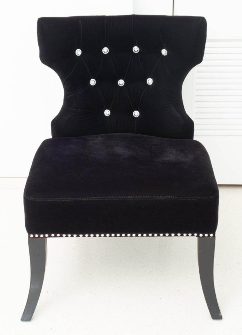 Modern Hollywood Regency style lounge chair upholstered in black velvet with rhinestone buttons, silver-tone metal grommets, and four ebonized cabriole legs. 
In good condition. Wear consistent with age and use.

Dimensions: 33