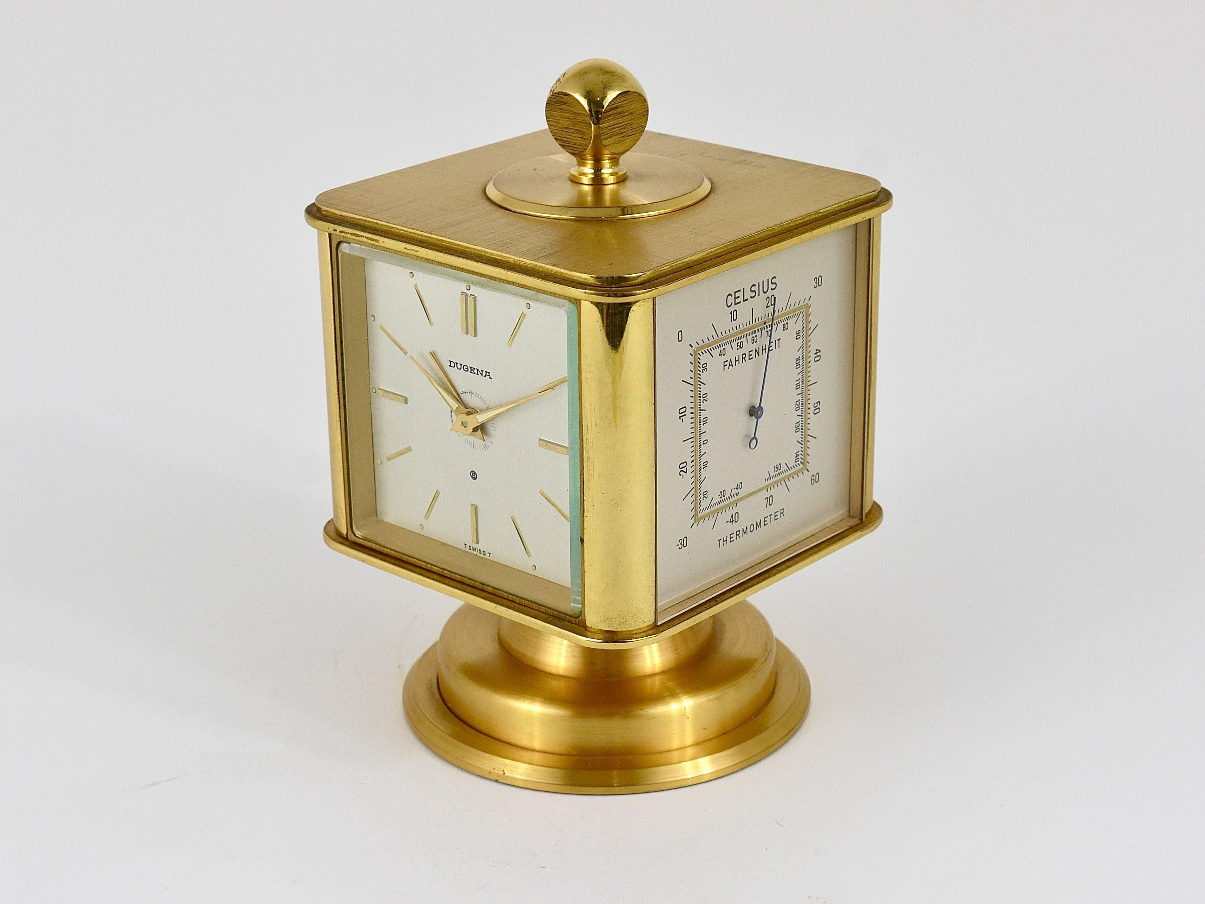 A beautiful cube-shaped brass alarm table clock which combines also an integrated thermometer, hygrometer and barometer. Executed by Deutsche Uhrmacher-Genossenschaft Alpina (DUGENA) in the 1970s. On a rotatable base with a Swiss made manual winding