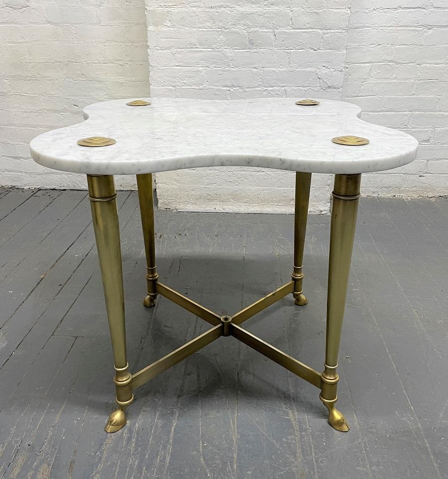 Hollywood Regency brass and Carrara marble table. Well-designed table with brass frame, a Carrara marble top, and claw feet.