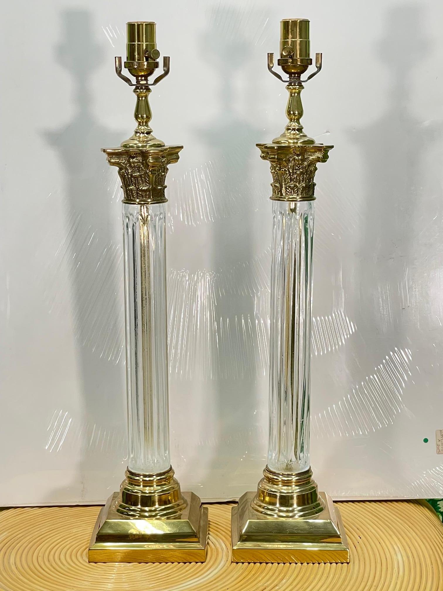 Pair of brass and crystal Roman column table lamps feature Corinthian capitals and fluted crystal shafts. Good condition with minor imperfections consistent with age, see photos for condition details.

