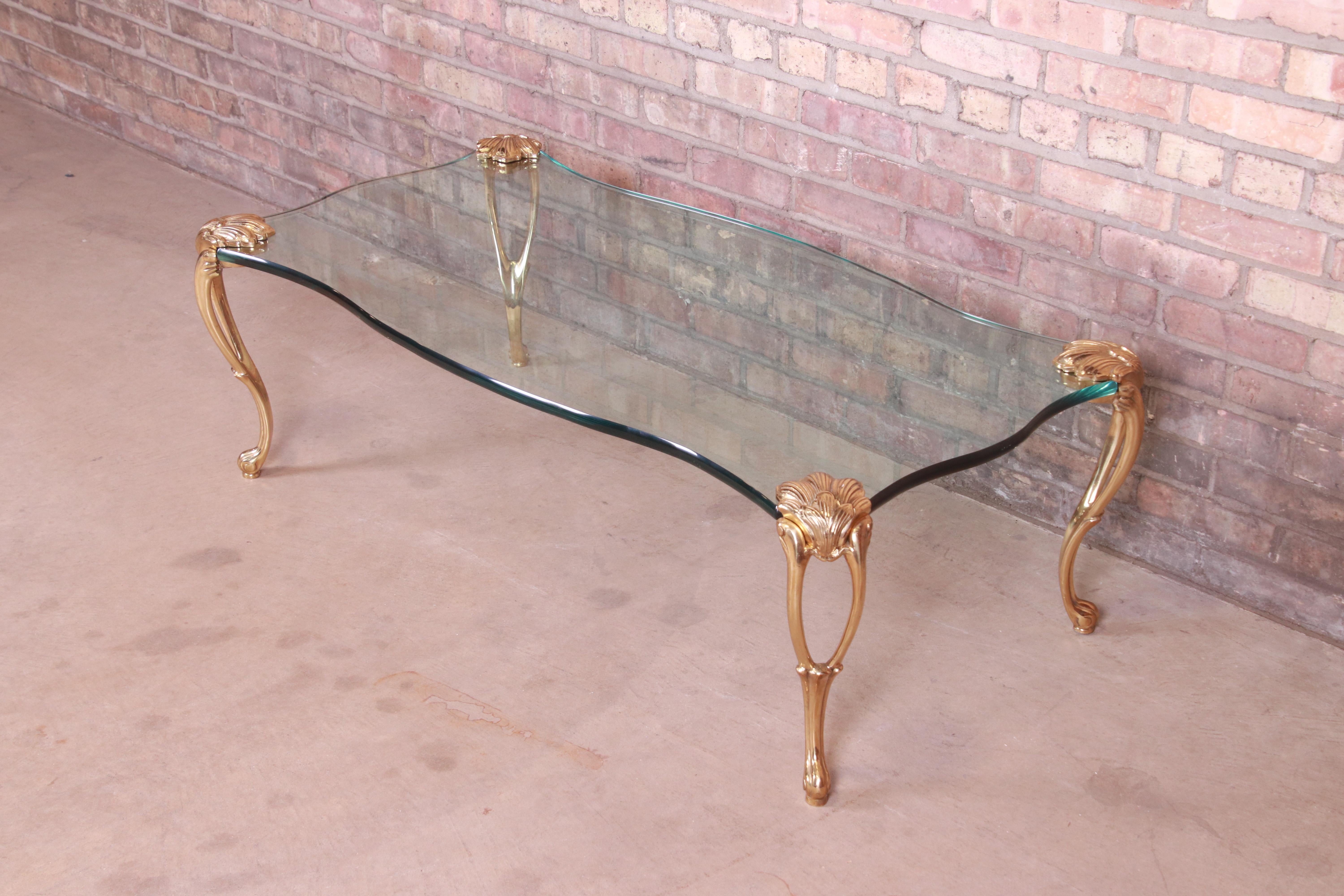 A gorgeous mid-century Hollywood Regency coffee or cocktail table

In the manner of P.E. Guerin

USA, Circa 1970s

Sculpted solid brass cabriole legs, with thick glass top in serpentine form.

Measures: 49.5