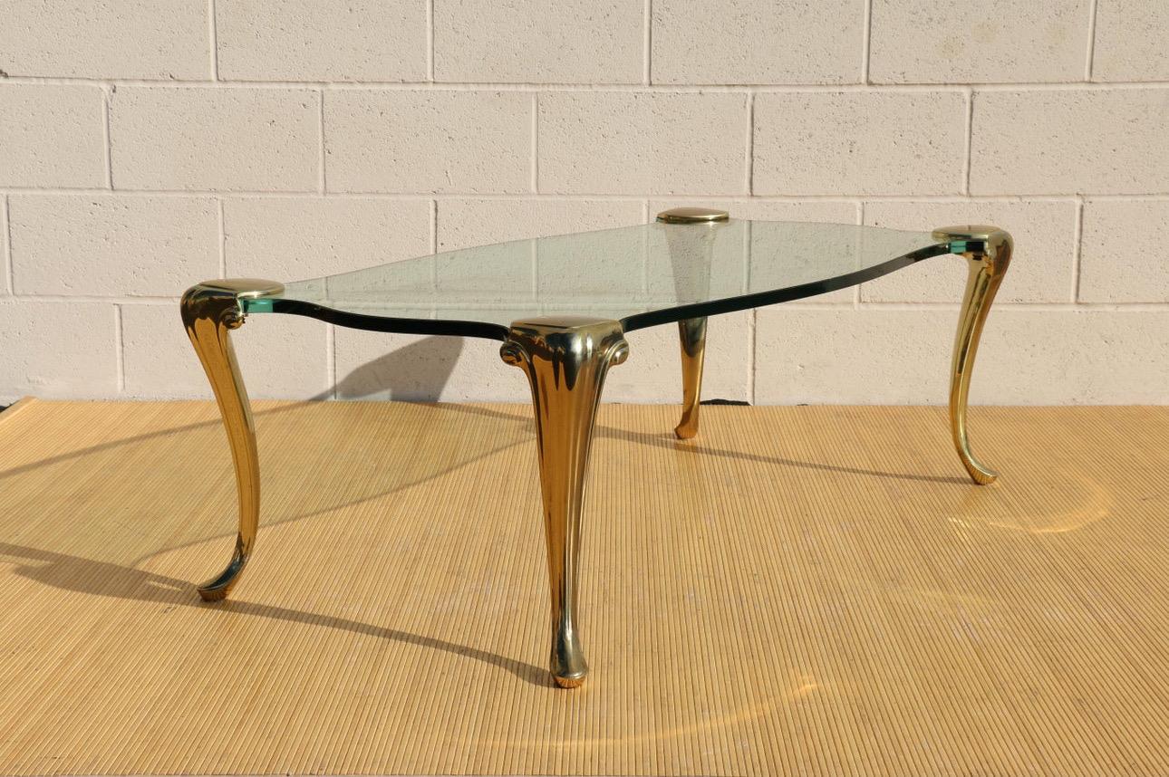 Superbe table basse de style Hollywood Regency Up&Up, composée d'un plateau en verre et de pieds en laiton massif. Cette table date des années 1970 et rappelle qu'elle est en bon état d'usage. Il présente quelques rayures mineures, pas vraiment