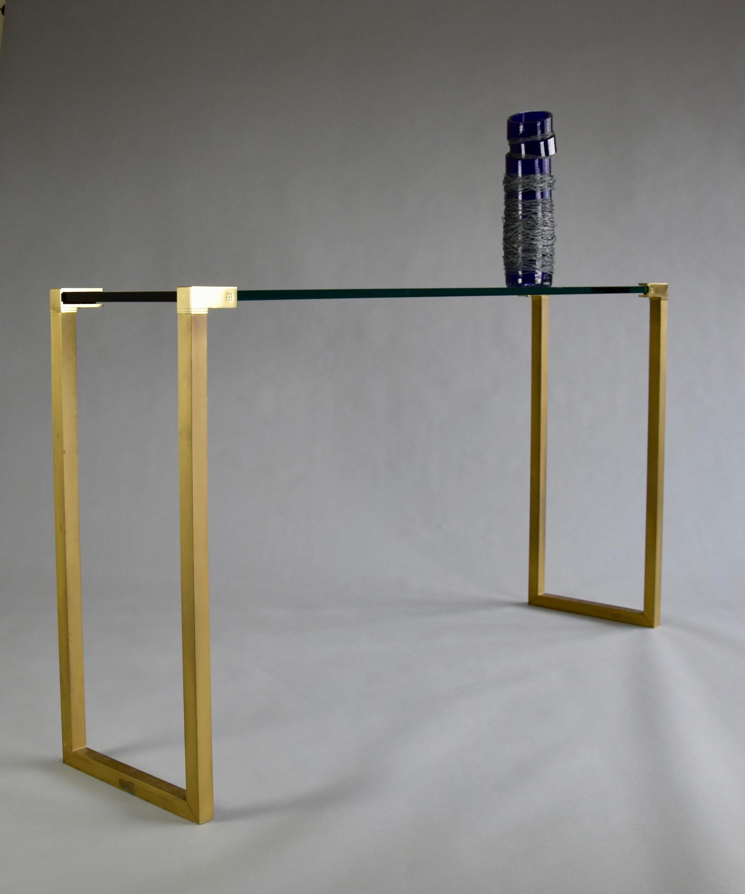 Elegant Hollywood Regency brass and glass console designed and produced in the 1980's by Peter Ghyczy. The console is in great condition and has just the right patina. The glass top has a minor chip on the back bottom which can only be seen if you
