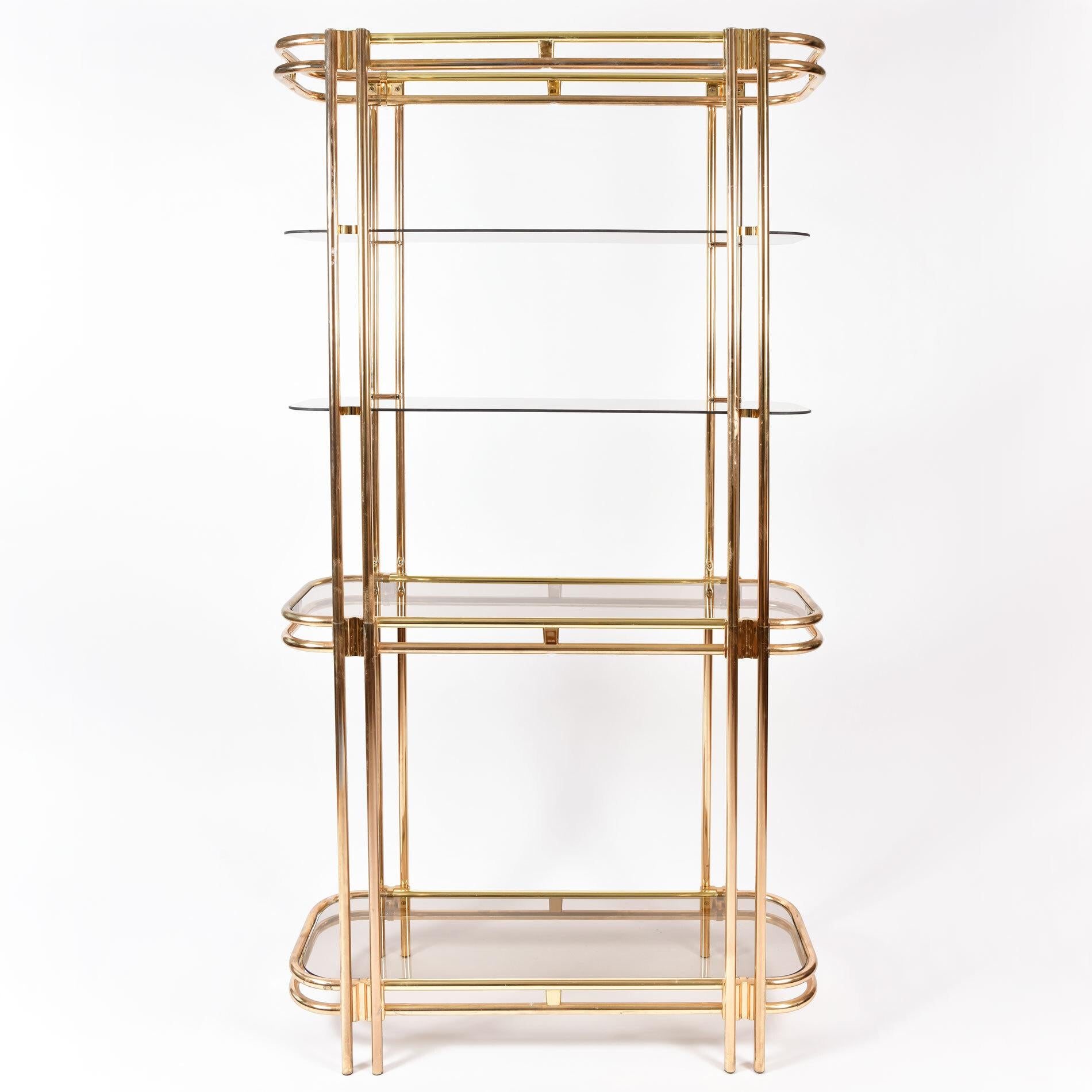 Tall 1970s American brass and glass shelving unit.

Curved brass frame with three levels of double brass shelving and two levels of single glass shelving.