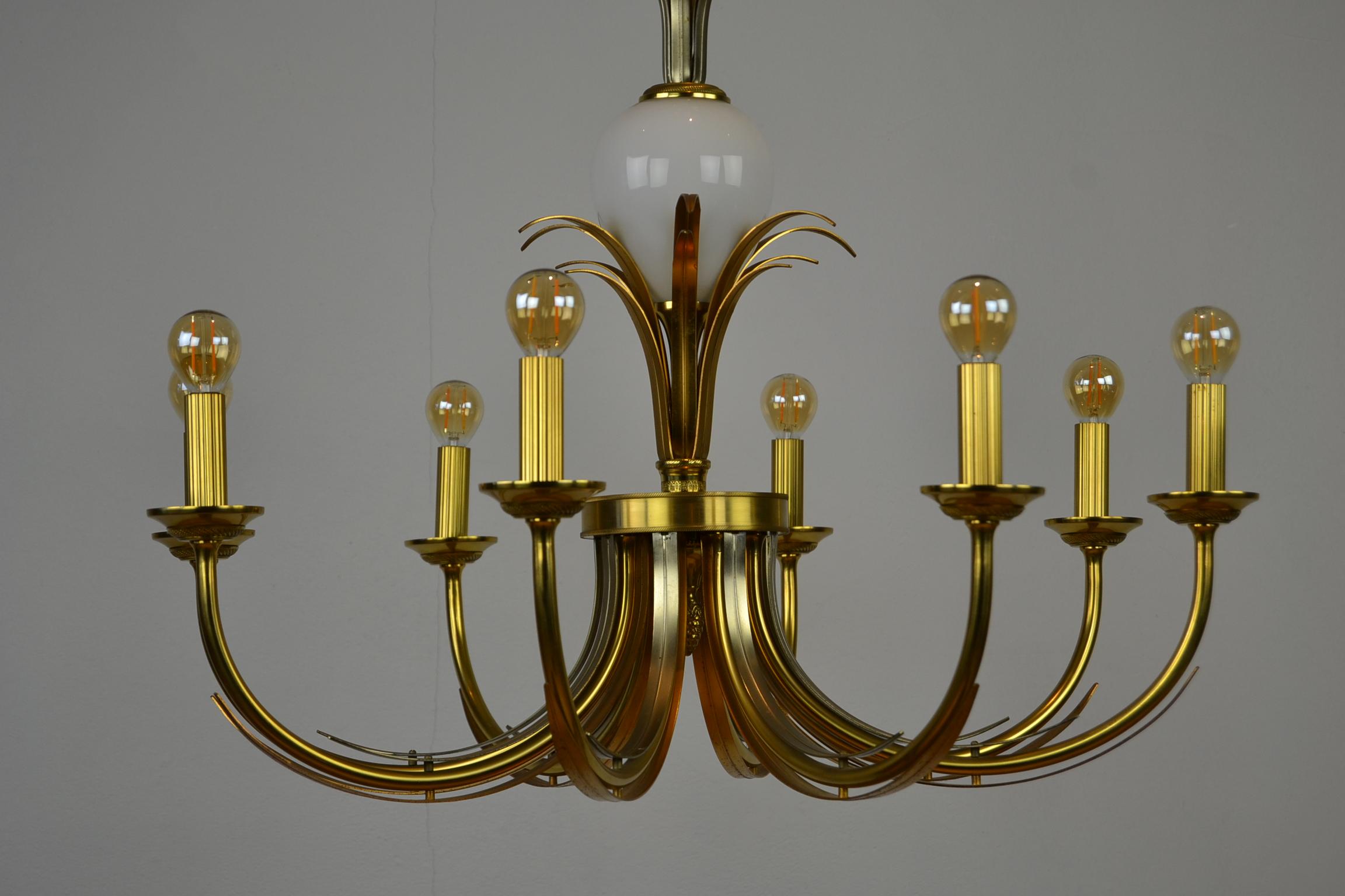 Hollywood Regency brass chandelier with glass ostrich egg from the 1970s
in the style of Maison Charles France or Boulanger Belgium.
 
This elegant ceiling light has 8 arms with gilded metal leaves and a large opaline glass ostrich egg in the