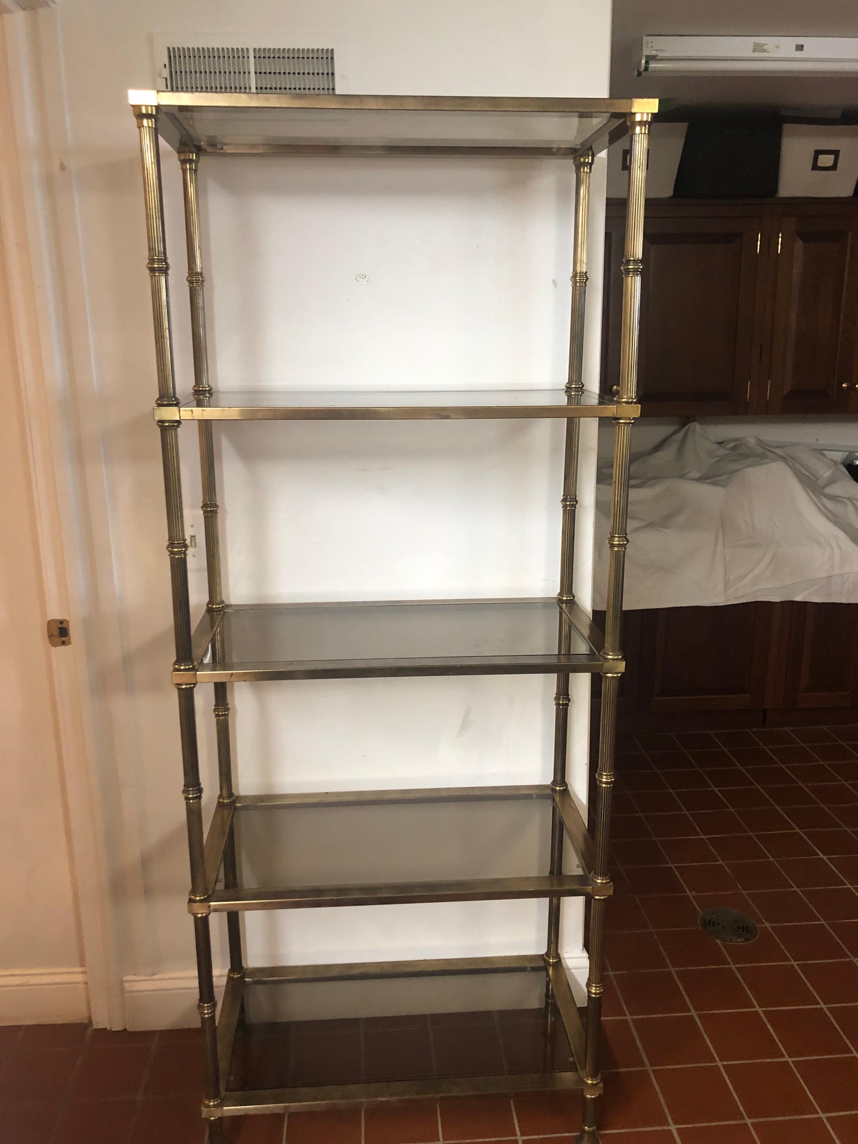 Hollywood Regency brass and smoked glass Etagere .
Classic timesless design. Consists of 5 shelves with removeable smoked beveled glass. Perfect to house your books and collectibles. Reeded columned sides give it a traditional corinthian feel. This