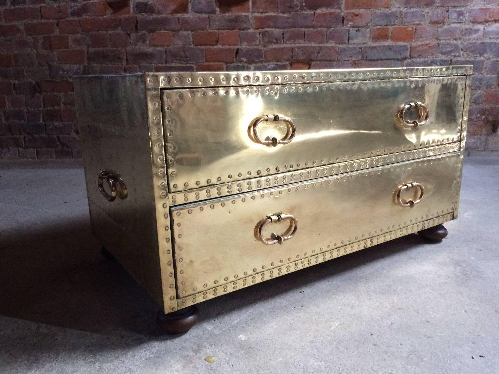A magnificent Hollywood Regeny brass clad chest of drawers (coffee table) with copper stud rivets made by Sarreid Ltd, heavy brass drop drawer handles with matching handles to sides, raised on bun feet, dating to 20th century.

Provenance: From