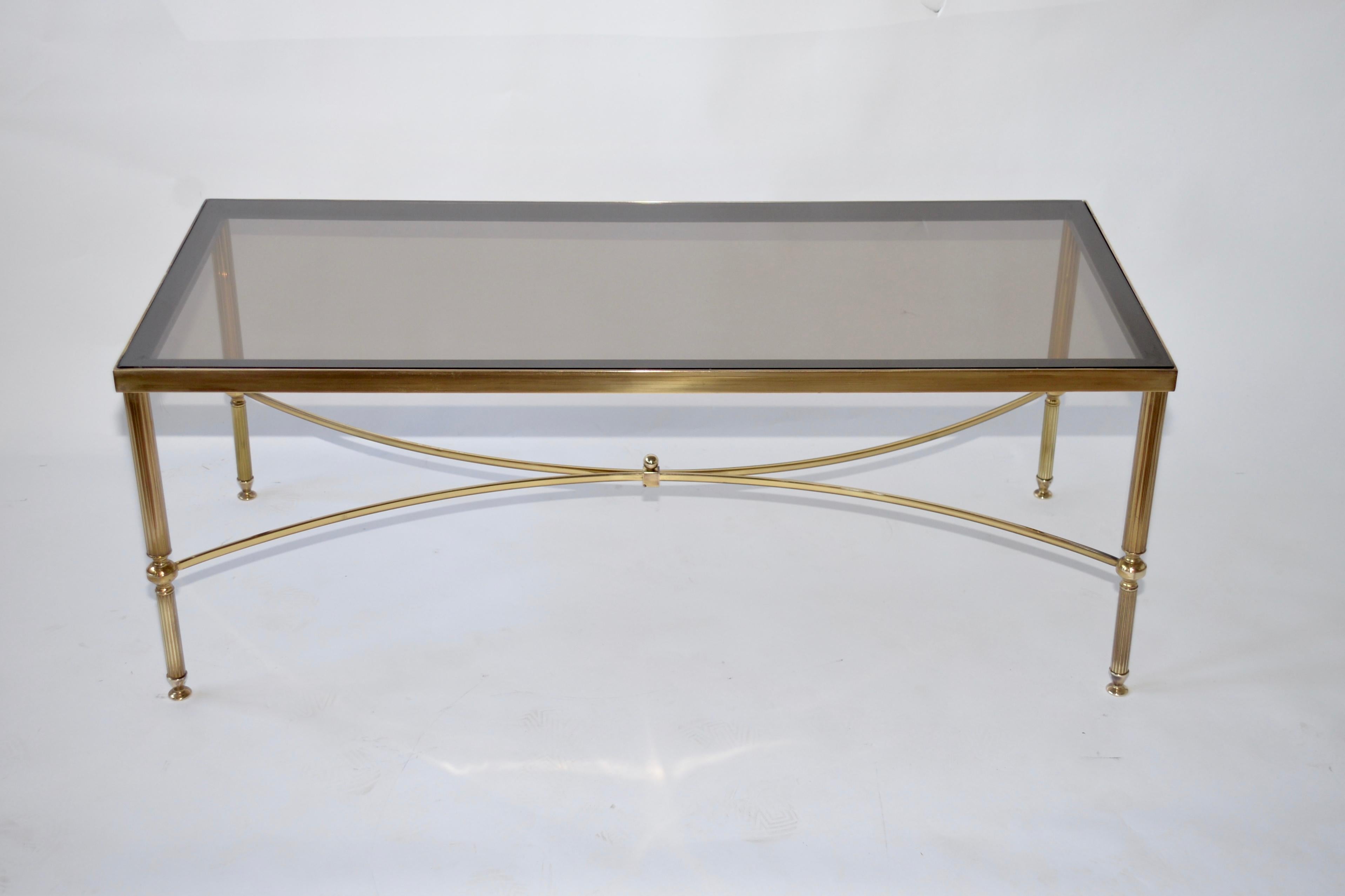 A Hollywood Regency style solid brass coffee table. Original smoked glass top with a border around the edge of the glass. Lovely original item.
          