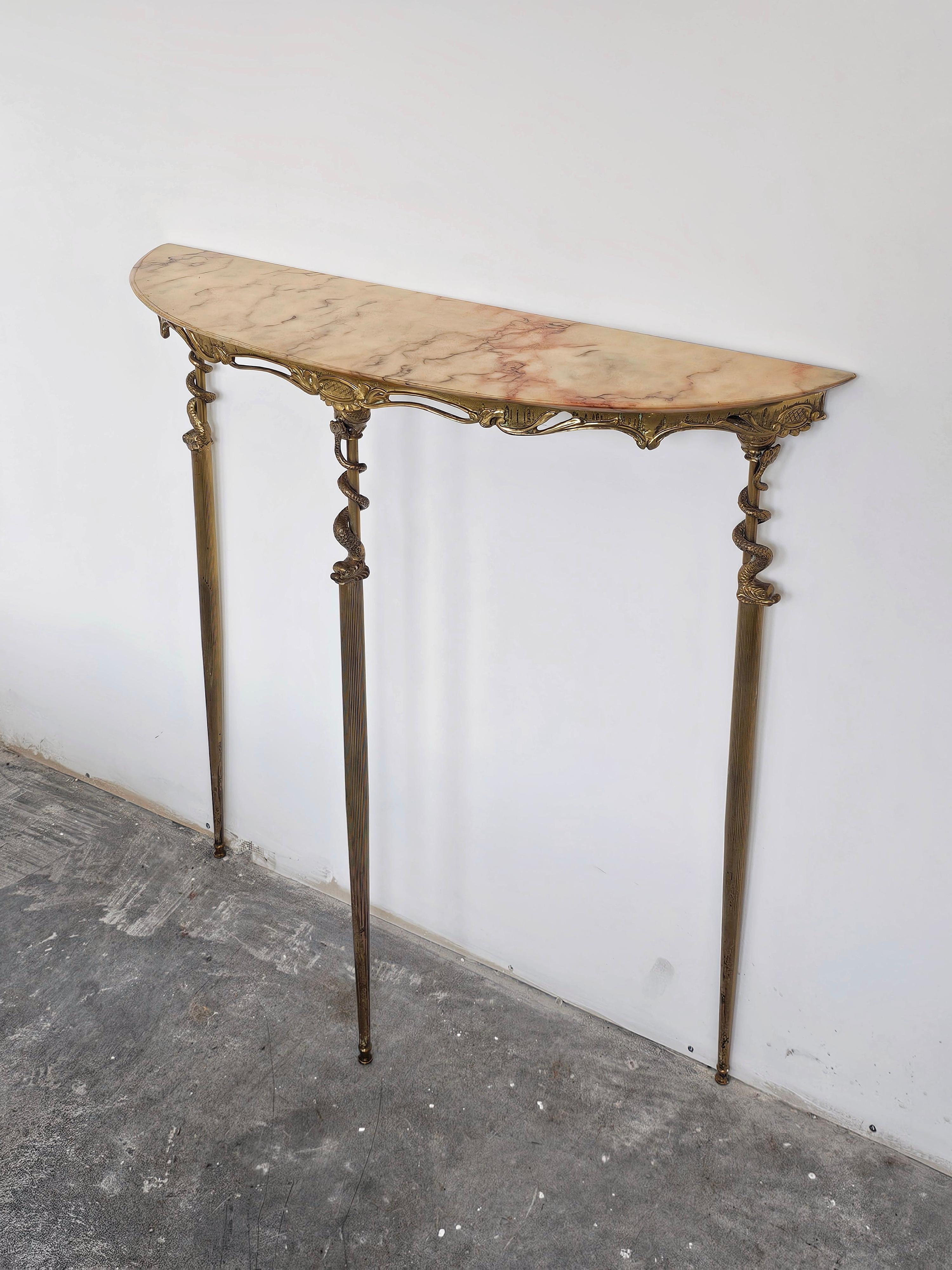 In questa inserzione troverai una bellissima consolle in ottone Hollywood Regency con motivo a serpente marino. Presenta un piano in marmo semicircolare color pesca. Realizzato in Italia negli anni '50. 

La console è in buone condizioni. La