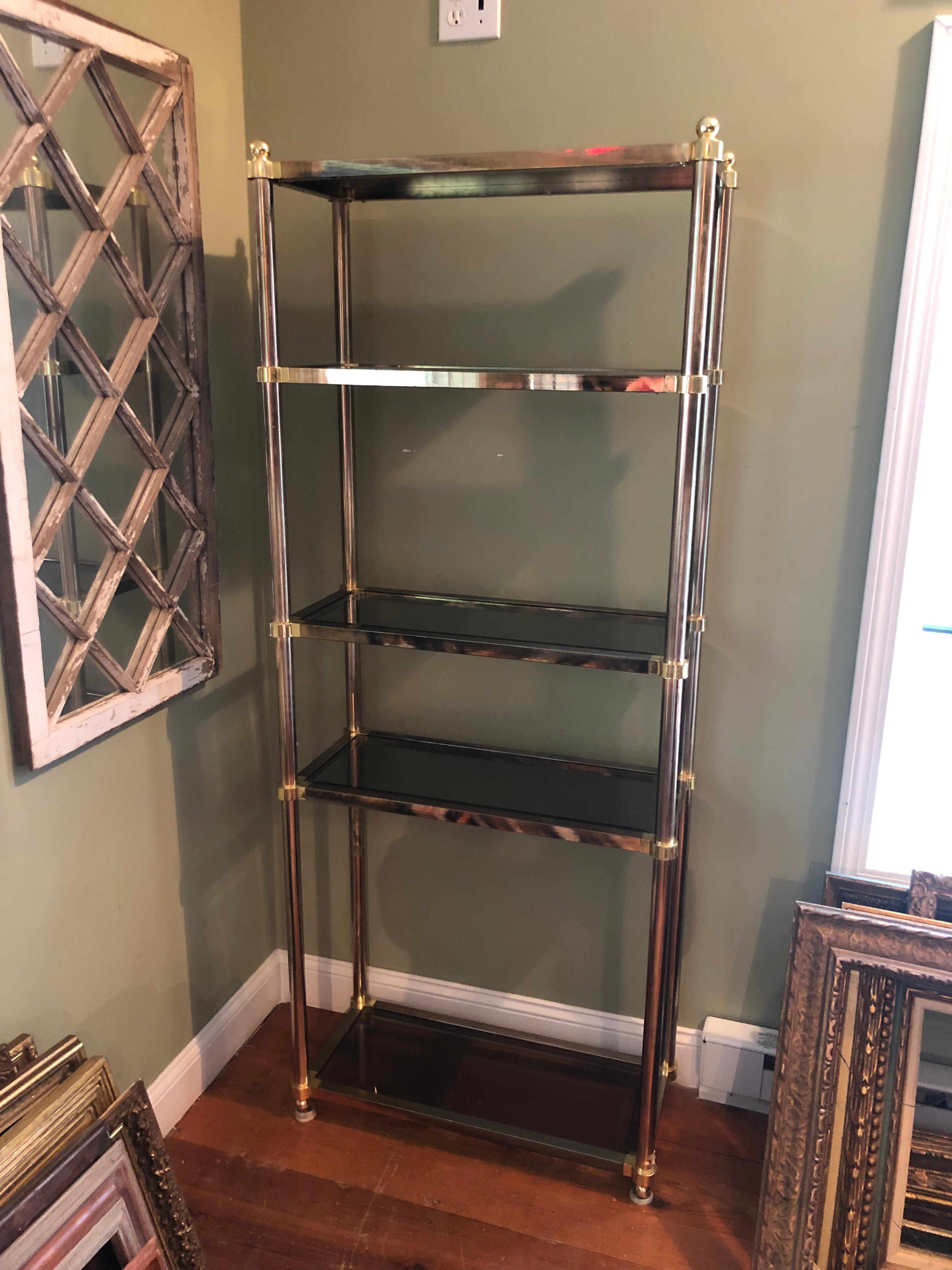 Hollywood Regency brass étagère with smoked glass. 5 smoked glass shelves. Classic styling for staging a home or shop. Some patina and wear to brass finish.