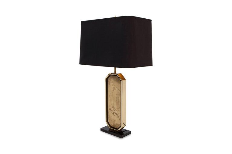 Hollywood Regency style lamp.

Brass etched artwork by Maho (attributed as alter ego of George Matthias).
Black glass center with 23-karat gold edges, black linen shade.

Belgium, 1980s.

Measures: H 80 cm, W 27 cm, D 43 cm.
