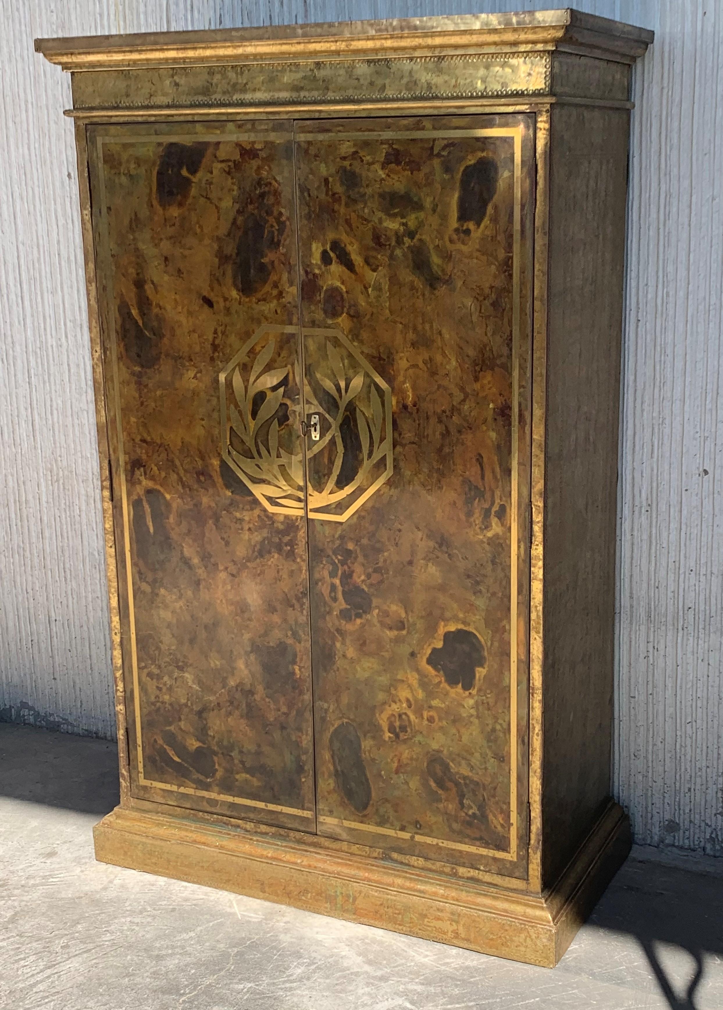 Mid-Century Modern drinks bar cabinet with nice brass faces with hammered brass nails, panels in a solid wood frame.
This piece its from the 1960s, beautiful oxidation that opens up completely.

The interior has a superior glass shelve, one