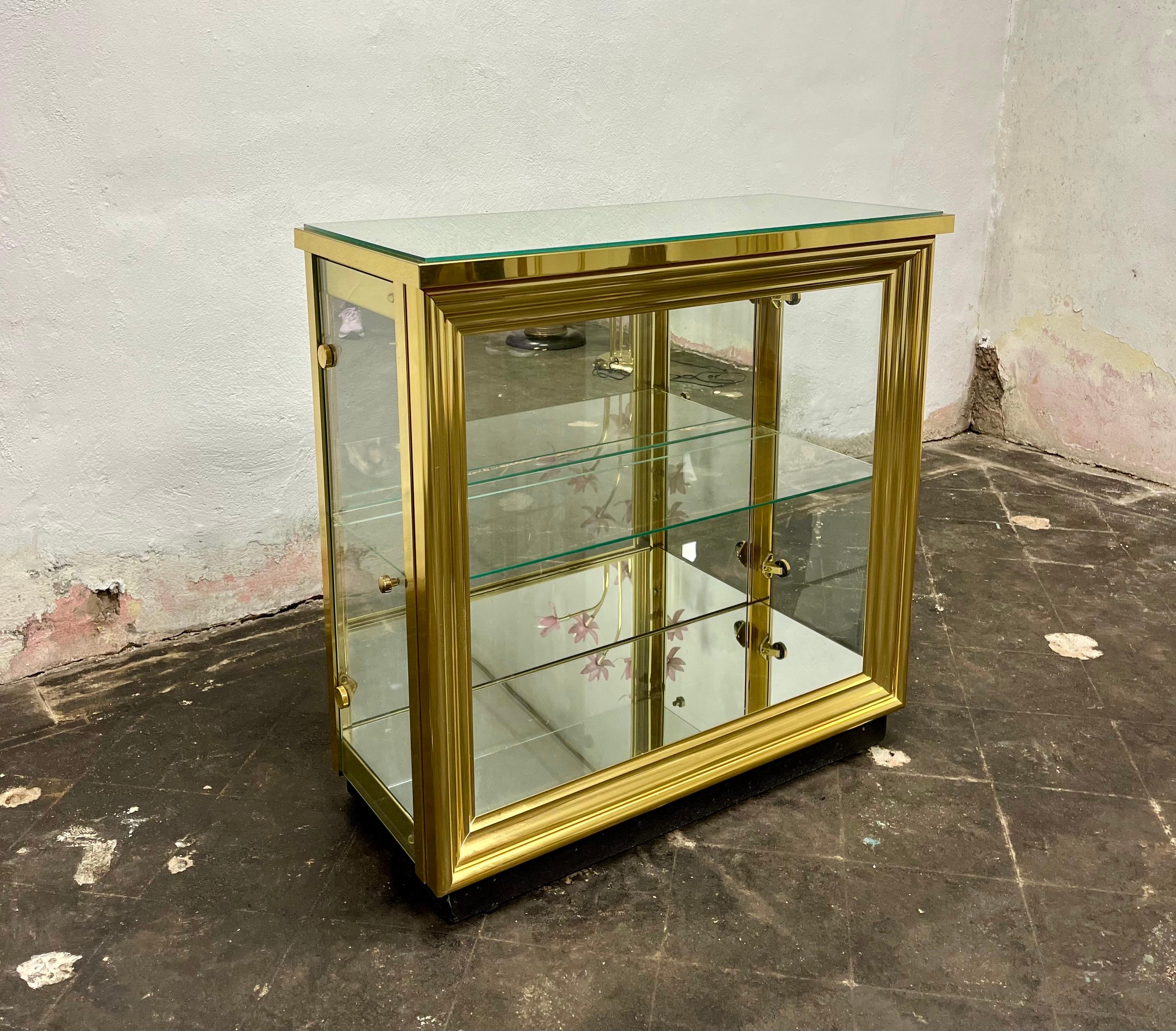 A sleek & modern display cabinet from Italy circa 1970s. It features mirrored top, bottom and back with glass doors on both sides. Framed brass frame with picture frame front. The unit lights up to create a moody feel. 
Curbside to NYC/Philly $400