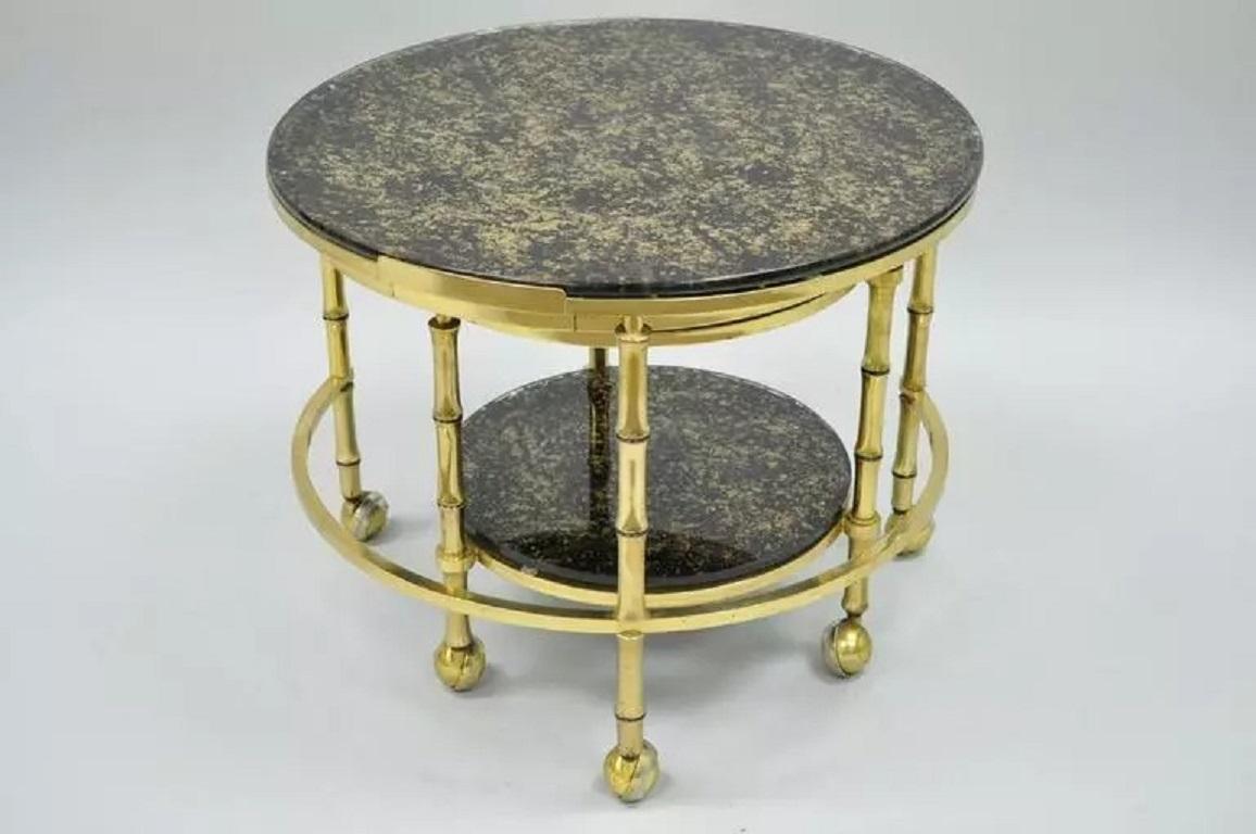 Tables gigognes vintage Hollywood Regency en faux bambou, laiton massif et verre. Cet ensemble unique se compose de trois cadres ronds en laiton faux bambou pliables/expansibles sur roulettes et de plateaux en verre noir décorés de mouchetures d'or.