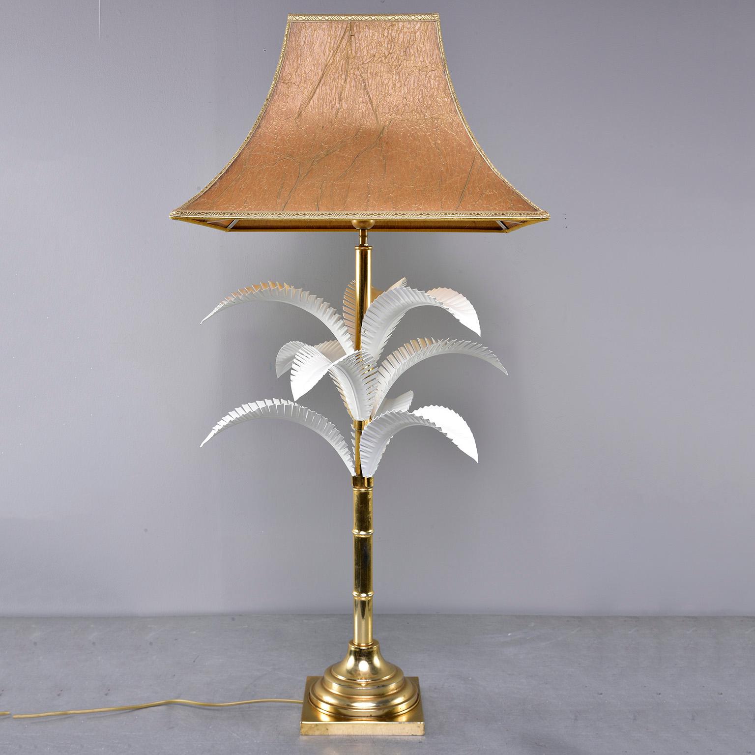 Table lamp by unknown maker was found in Italy, circa 1970s. Brass base, shaft has faux bamboo details and enameled white metal palm fronds. Parchment shade, toggle switch cord. Wiring and plug updated for US electrical standards.

Measures: Shade
