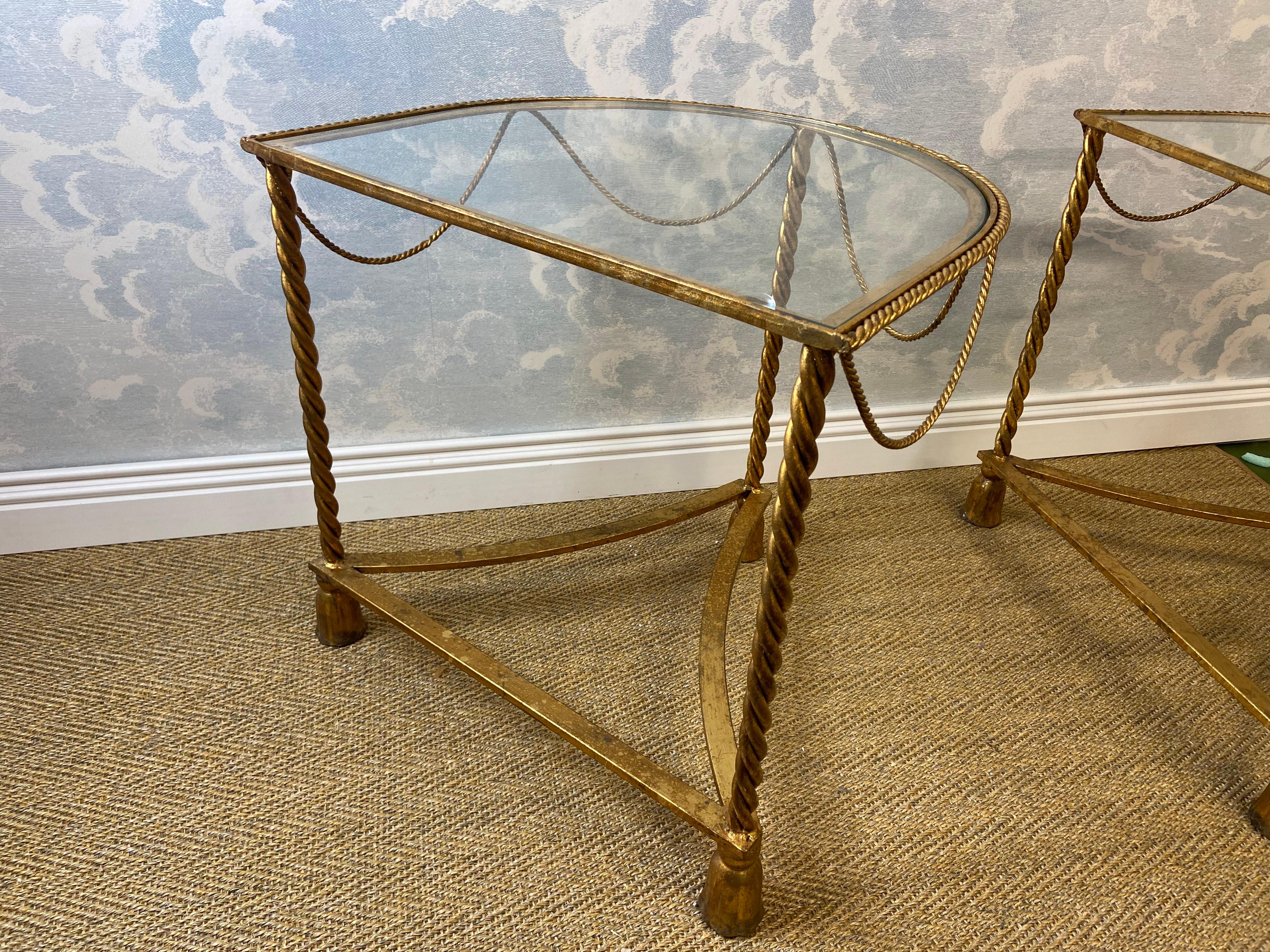 This attractive pair of side tables with gilded metalwork frames and bent rope details probably hails from Italy in the the 1970's and is attributed to Li Puma in Florence. 

Set on three feet with tassel detail, the frames hold the original custom