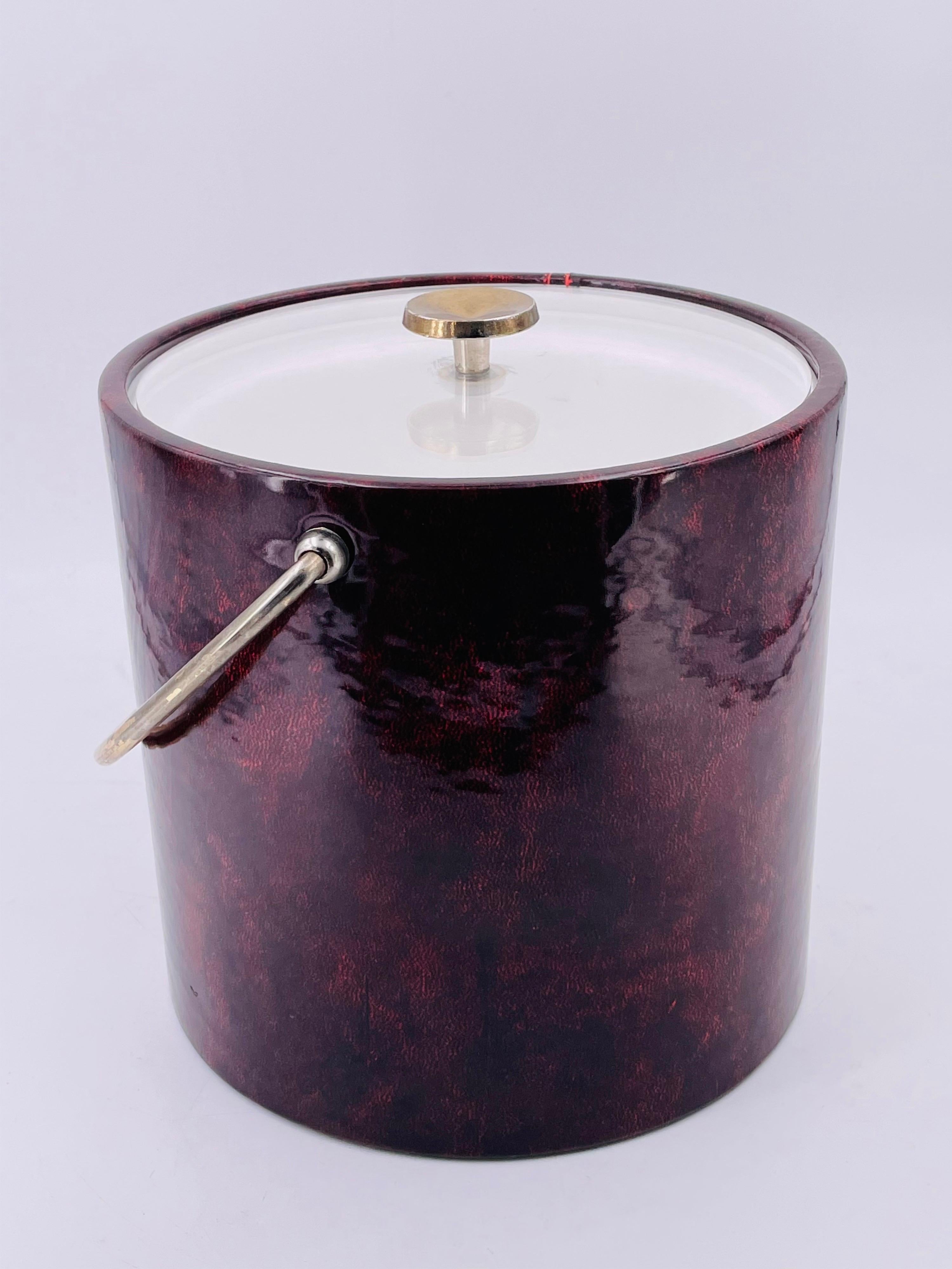 A beautiful ice bucket with brass plated handle and top in lucite, wrapped in Burgundy faux leather naugahyde great condition some wear on the brass due to age, circa 1960's.