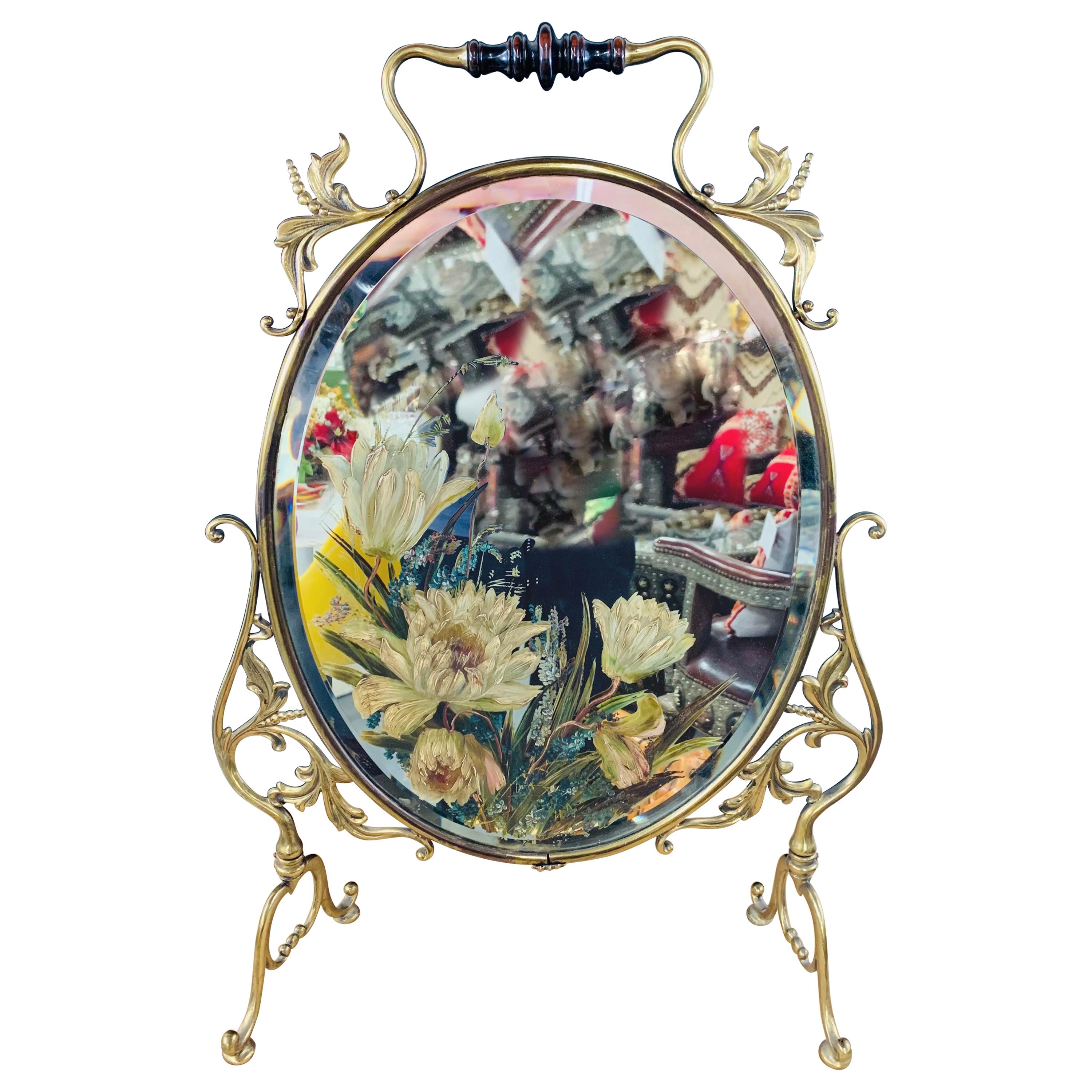 A lovely oval brass Art nouveau  mirror. The mirror features a wooden handle and fine brass frame in a very elegant floral design and is gracefully setting on a four legged base. The mirror glass is beveled and shows an amazing blooming flowers