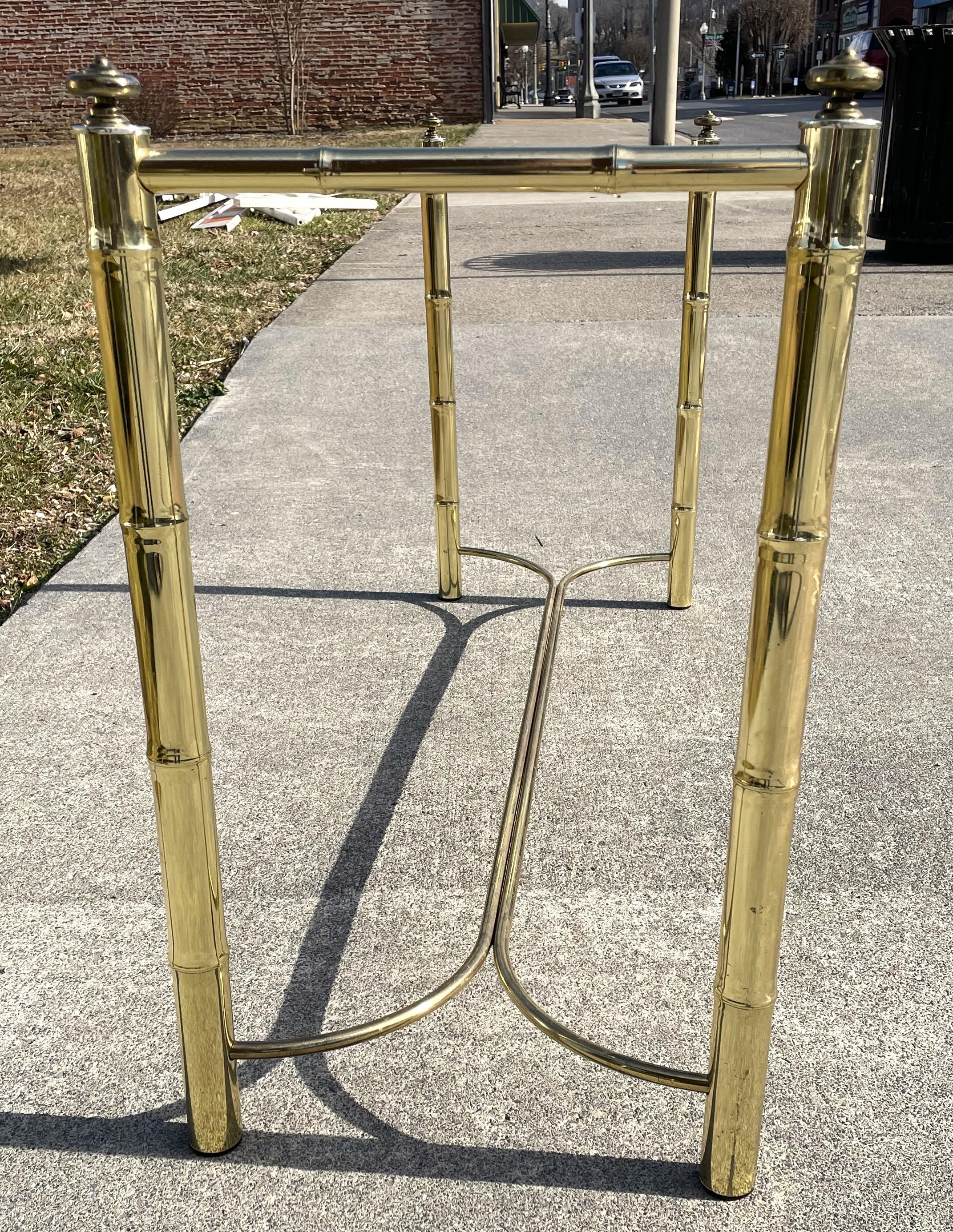 Here is a decorative brass plated, faux bamboo style metal console table with a smoked glass top. The glass could possibly be a replacement since it is not as long as the space it is set in, the glass measures 46 inches by 14 inches and the space is