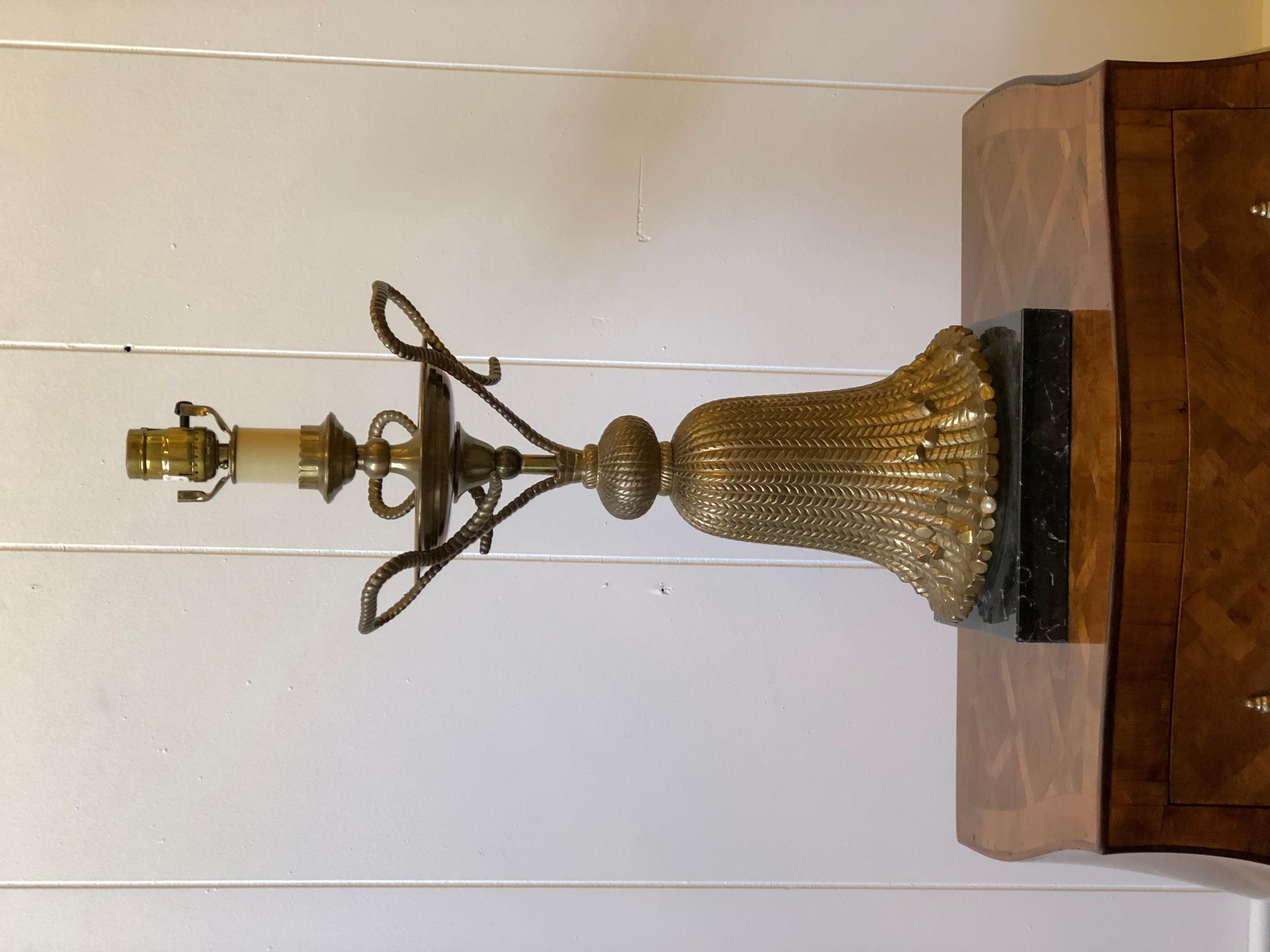 Late 20th century table lamp made of cast brass rope and tassels, and mounted on a black marble platform base. Made by Chapman in the Hollywood Regency style.