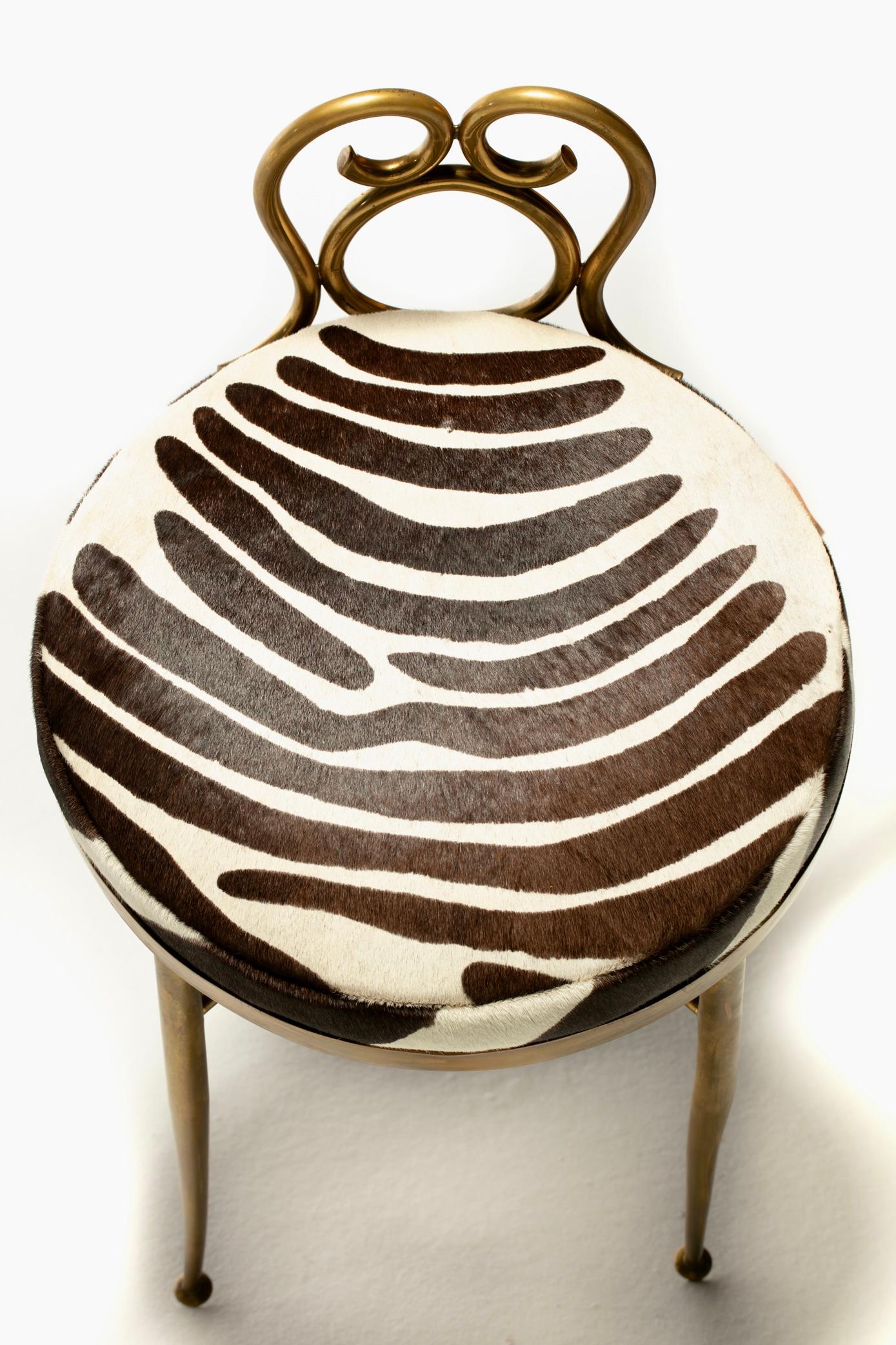 Elegant from all sides and exuding sex appeal all over is this Tommi Parzinger style Hollywood Regency vanity or dressing stool made of brass and finished in zebra print cowhide. Put on that sexy silk robe and have a seat in pure luxury. This 1960s
