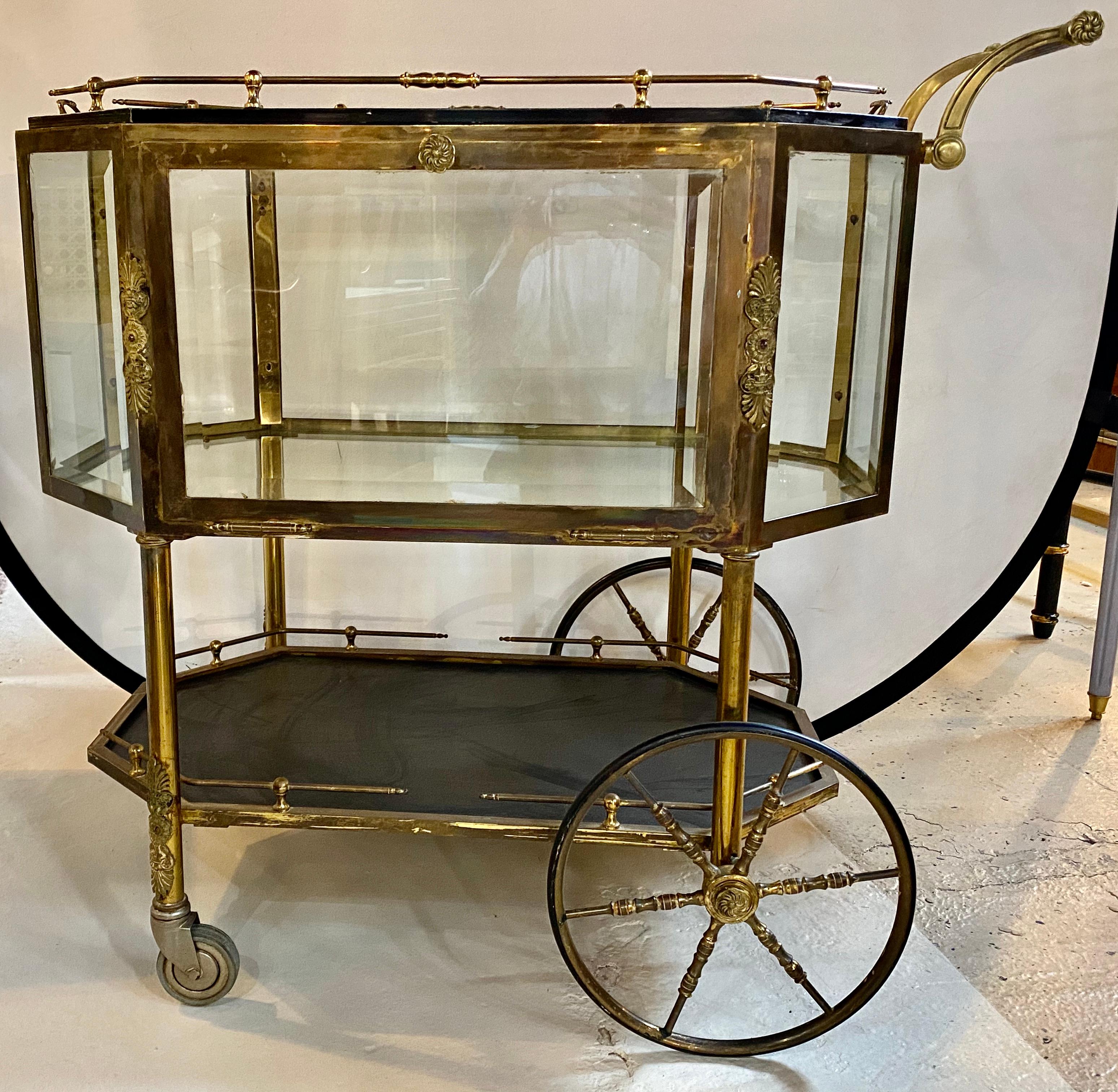 Hollywood Regency bronze tray top beveled glass showcase serving cart or wagon
The large brass wheels make this rolling cart easy to maneuver and give the whole a palatial look. The all beveled glass case having pull down sides to allow for easy