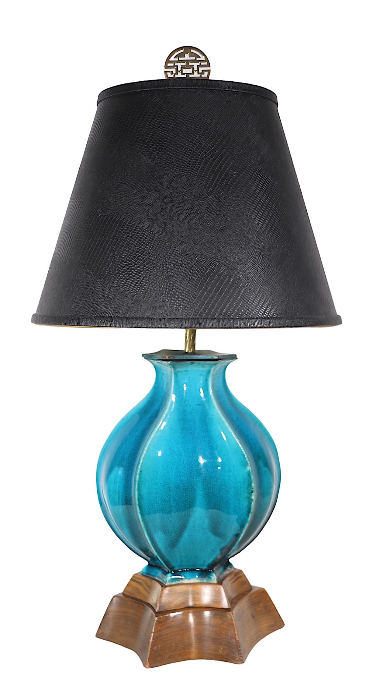 High Style Hollywood Regency style table lamp having a bulbous  six sided ceramic vase body, mounted on a stylized custom wood plinth base. The lamp was executed in a high gloss cerulean blue crackle finish, the two tier plinth base mirrors the form
