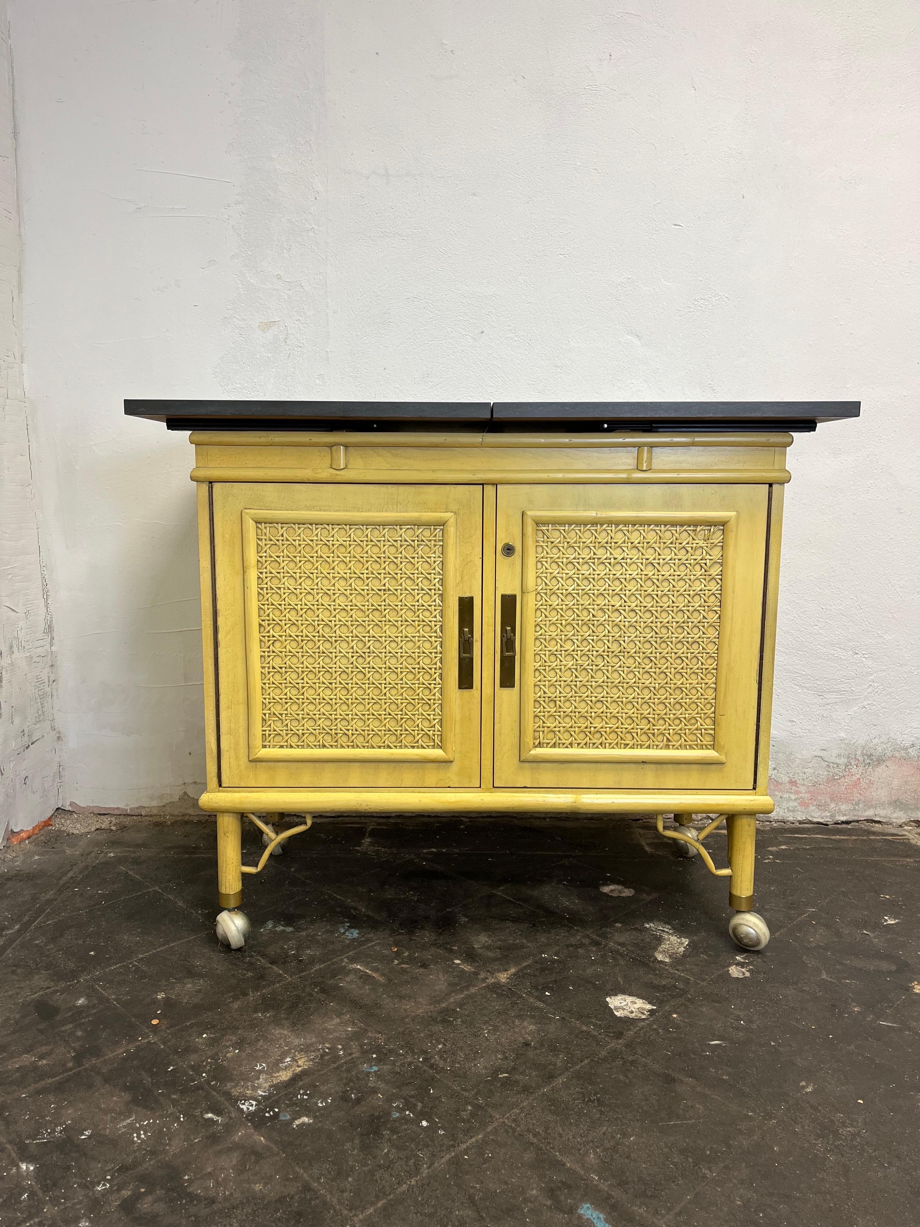 Beautiful bamboo framed Chinoiserie server with formica slate sliding top. Two open storage areas underneath with pegs for interior shelves. Beautiful yellow with brass detail pops. Finished back to allow for floating in room. Large casters for ease
