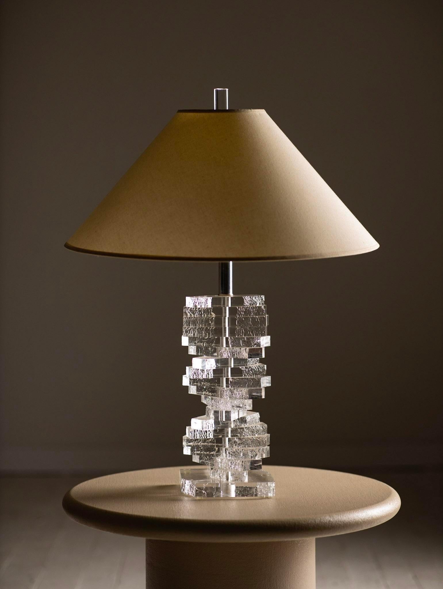 A staple in the Hollywood Regency style, this cascading lucite lamp will add a touch of metropolitan glamour to any space. Textured edges give this piece a unique quality like that of melting ice. Shade not included. Height of sculptural base